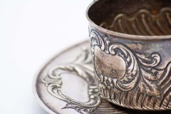 Cup and saucer in silver embossed with geometric figures and monogram card