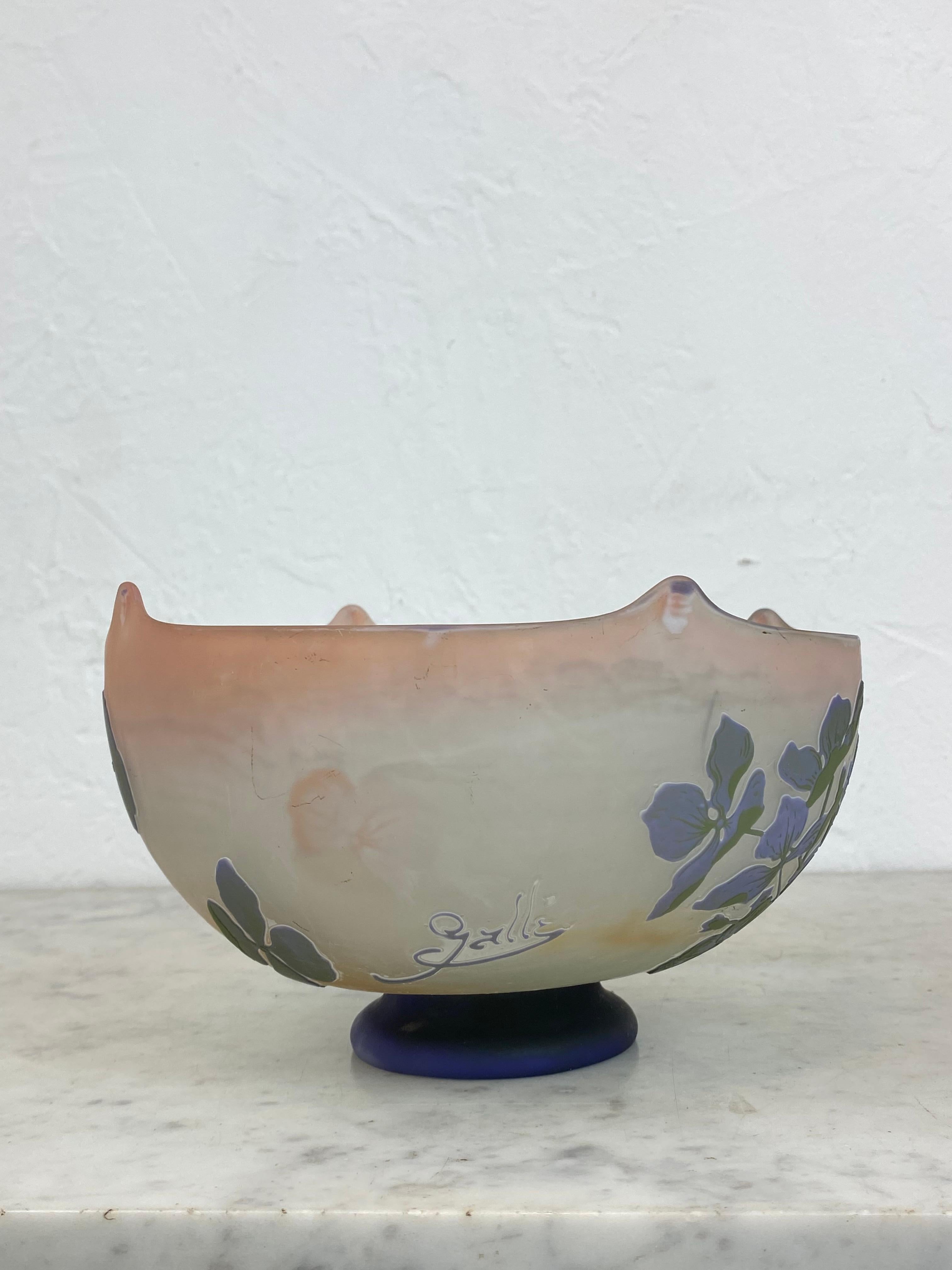 Coupe sur pied en verre multicouche, à quatre pointes épinglées à chaud, à décor floral dans les tons de violet et de vert sur fond rose. Signature de Galle sur le côté France 20e siècle