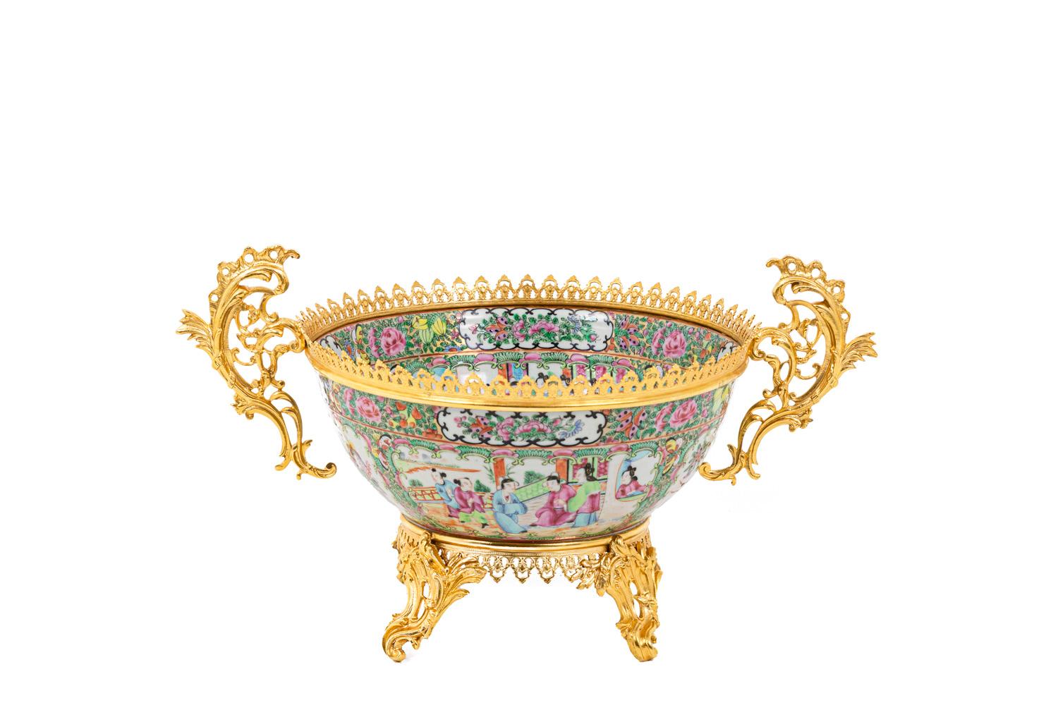 Basin-shaped cup in Canton porcelain. Decor of four large cartouches framing Chinese style every day life scenes on a white background filled with roses and other vegetal scrolls. Lateral handles shaped as openwork vegetal scrolls in chiselled and