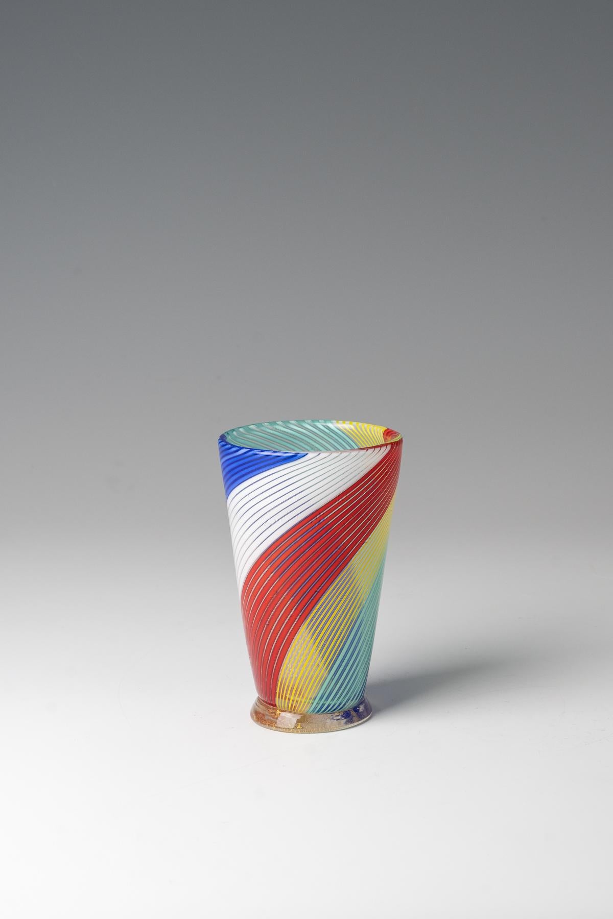 Vaso a coppa ''mezzafiligrana'' Aureliano Toso (attribuito), Murano, anni '50 Vetro incolore, con fili di vetro multicolore fusi in diagonale. Piede attaccato in incolore con fusione in lamina d'oro. H. 13 cm.

Ottime condizioni