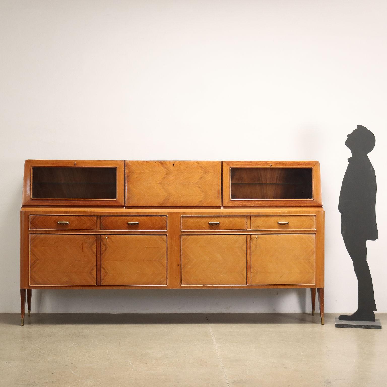 Cupboard with flap and hinged doors, visible drawers; exotic wood veneer, glass and brass.