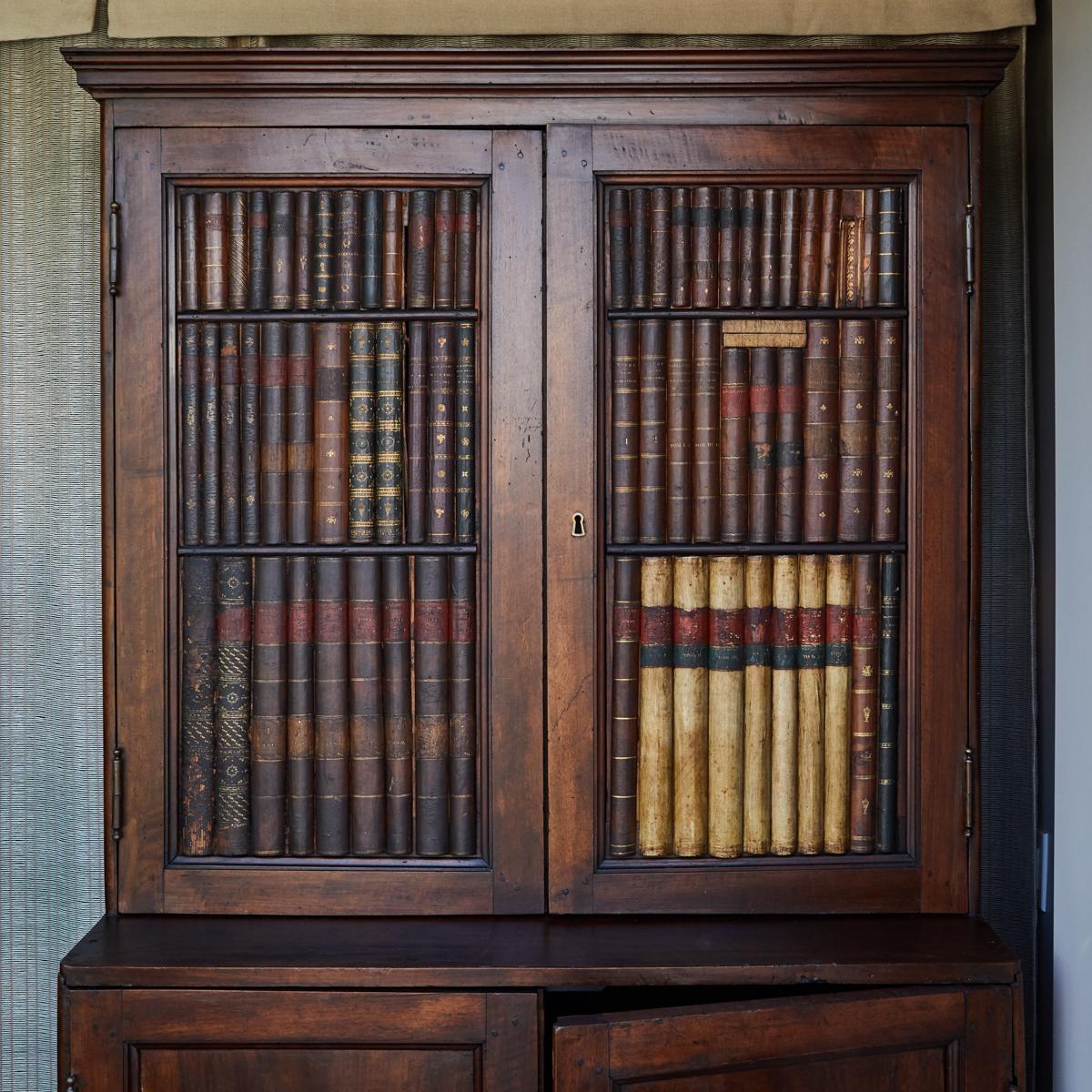 Early 19th-century Italian wooden cupboard with the unique feature of trompe l'oeil carved book spines, giving the appearance of a full library. The acquired patina has further enhanced this effect, accentuating the craftsmanship at play.

Italy,
