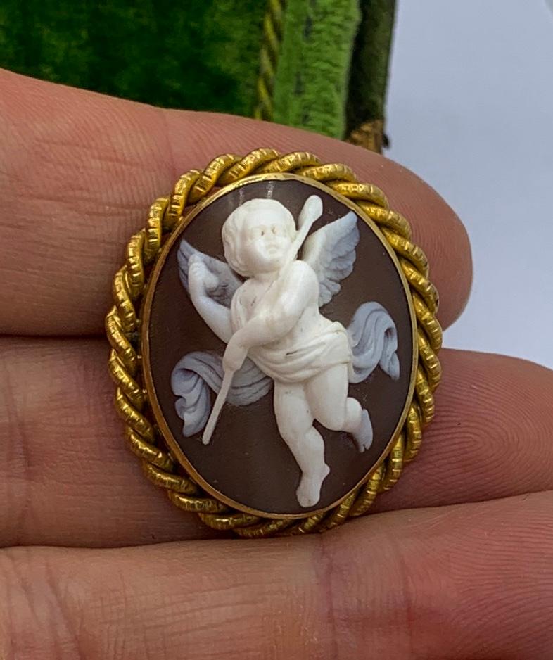 This is an absolutely stunning antique Victorian - Belle Epoque Shell Cameo Brooch Pin with a high relief carving of a Cherub,Cupid, Angel, or Eros set in a beautiful braided motif halo in 18 Karat Yellow Gold.
The cameo is of extraordinary beauty. 