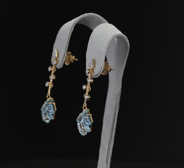 A stylish pair of Leaf Carved Blue Topaz Earrings accented with diamond in a cupid's arrow shape. 14K Yellow Gold. Diamond Weight: 0.46 carats,  Blue Topaz Weight: 12.15 cts, Length: 1 & 5/8” Metal type and stones can be customized. 