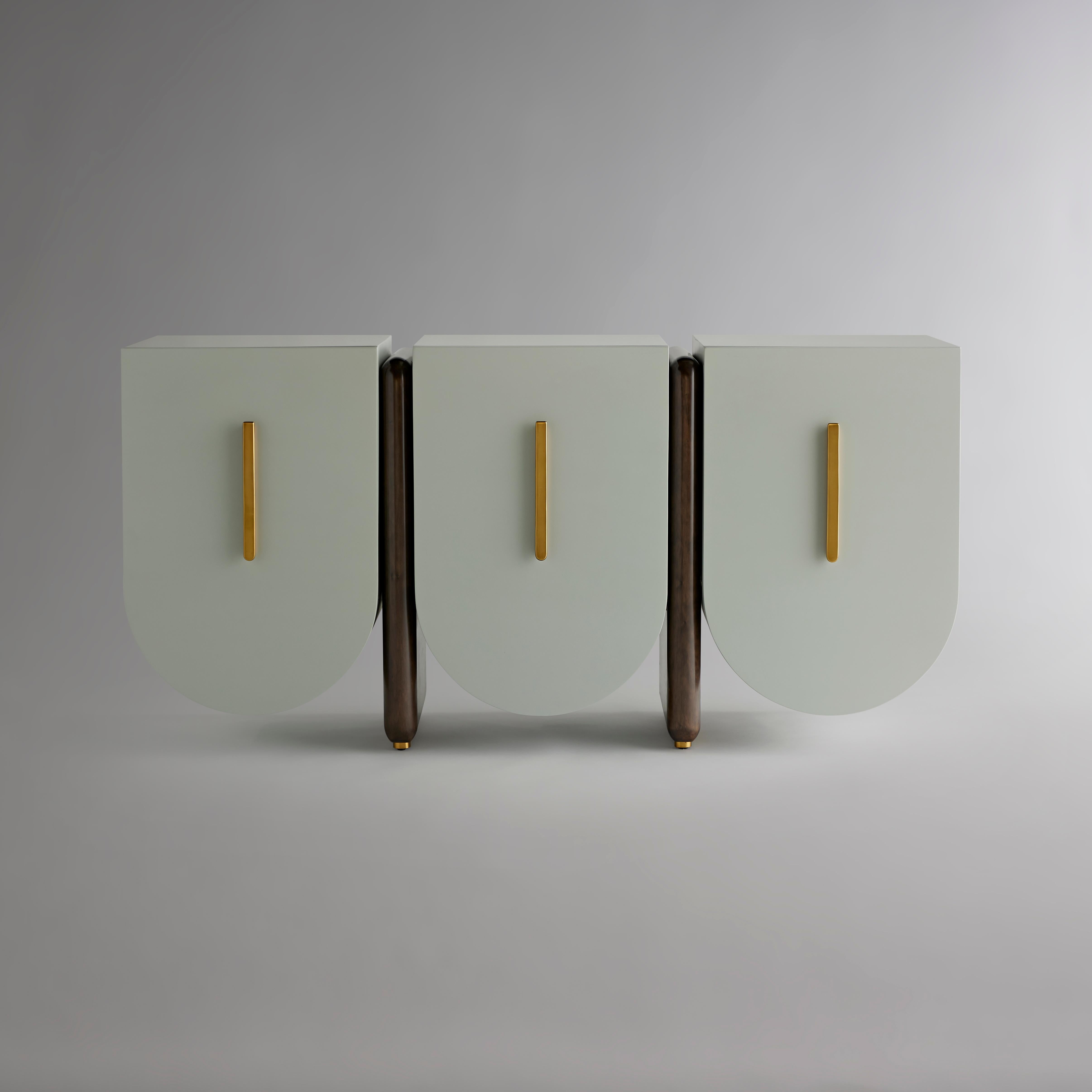 This striking piece offers exceptional functionality. Three curved cabinets open to reveal shelves. Within the center case lies a soft-close drawer for silver or fine cutlery. The lowermost is rounded to hold table linens. Brass plinths are matched