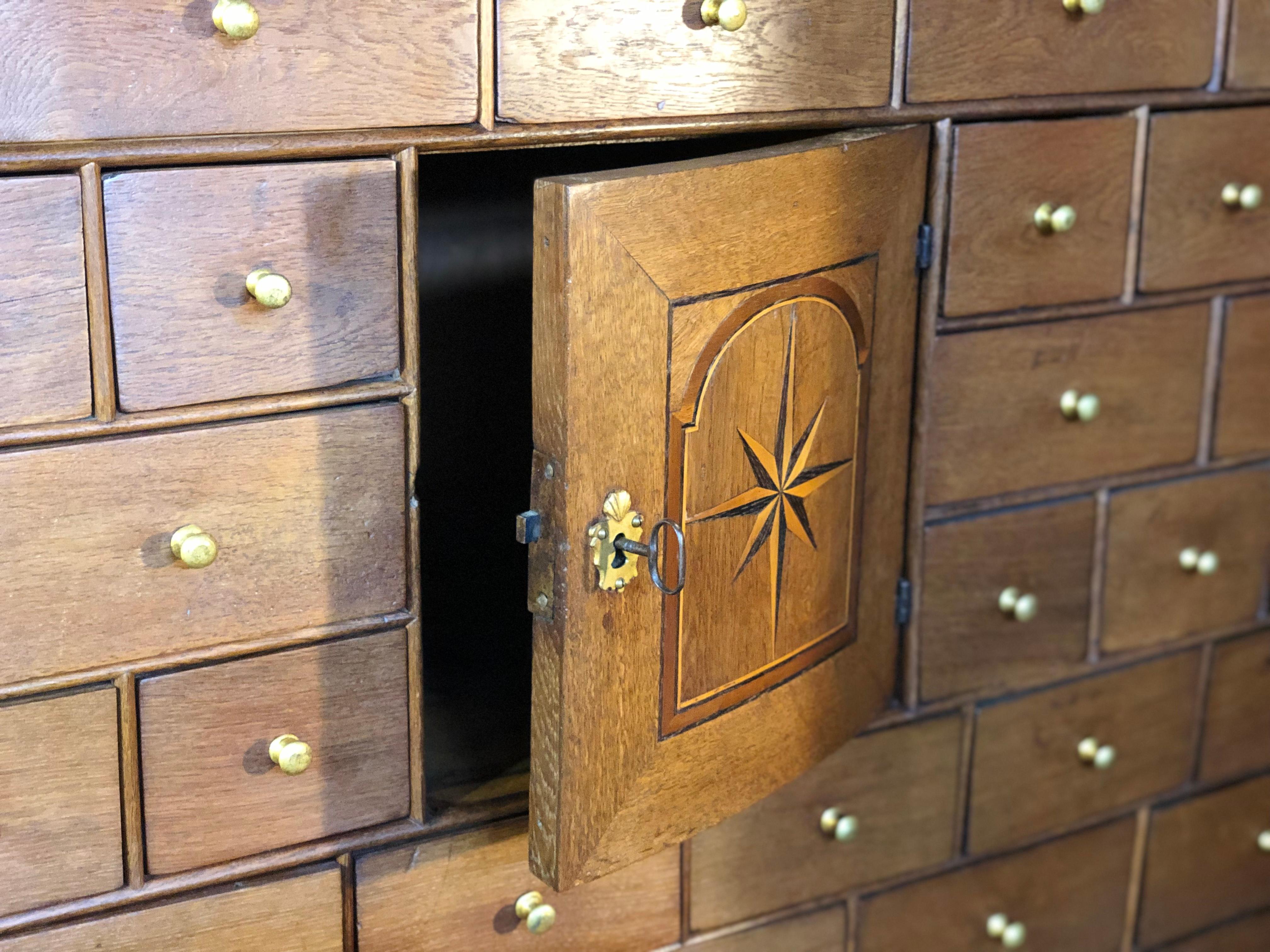A very late 18th to early 19th century Scandinavian Curiosity cabinet. Handcrafted in European oak with original hand forged metal work and keys. Some lovely inlay to the central focus cabinet door surrounded by multiple various sized drawers. This