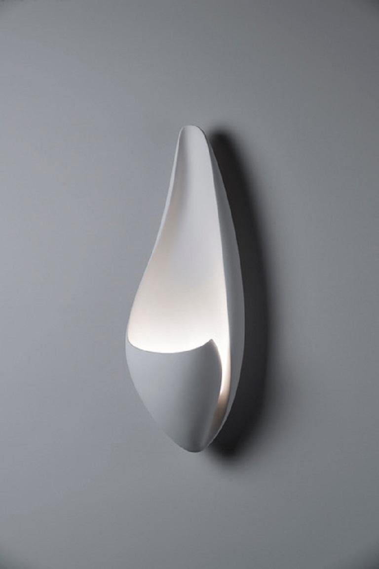 Handmade Curl wall light or sconce, in silky smooth white plaster, created by artist Hannah Woodhouse in her London studio. Contemporary design inspired by nature and mid-century European sculpture. The Curl wall sconce not only provides soft