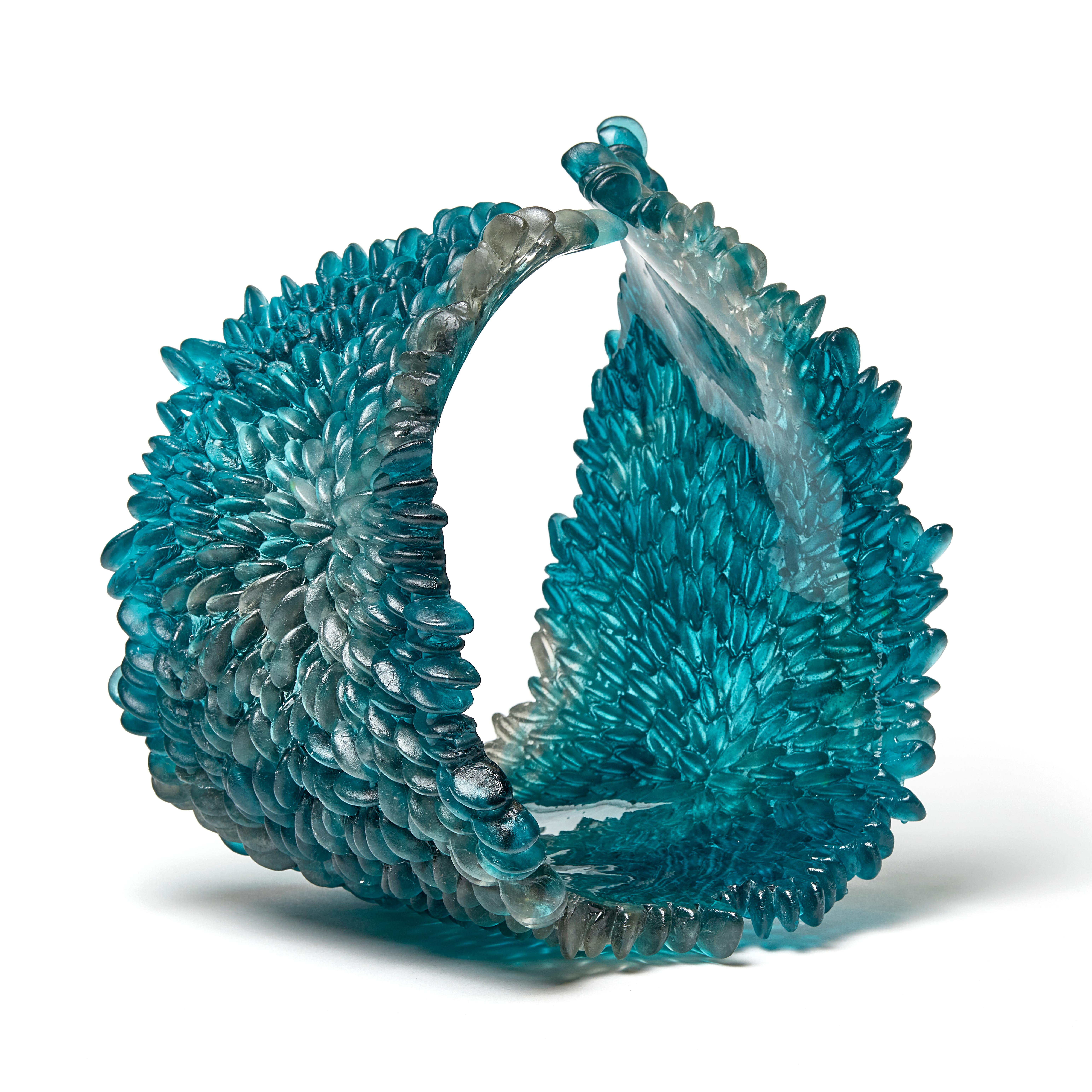 Curled Over IV is a unique textured glass sculpture in teal blue / deep aquamarine and grey by the British artist Nina Casson McGarva. 

Casson McGarva firstly casts her glass in a flat mould where she introduces all of the beautifully detailed,