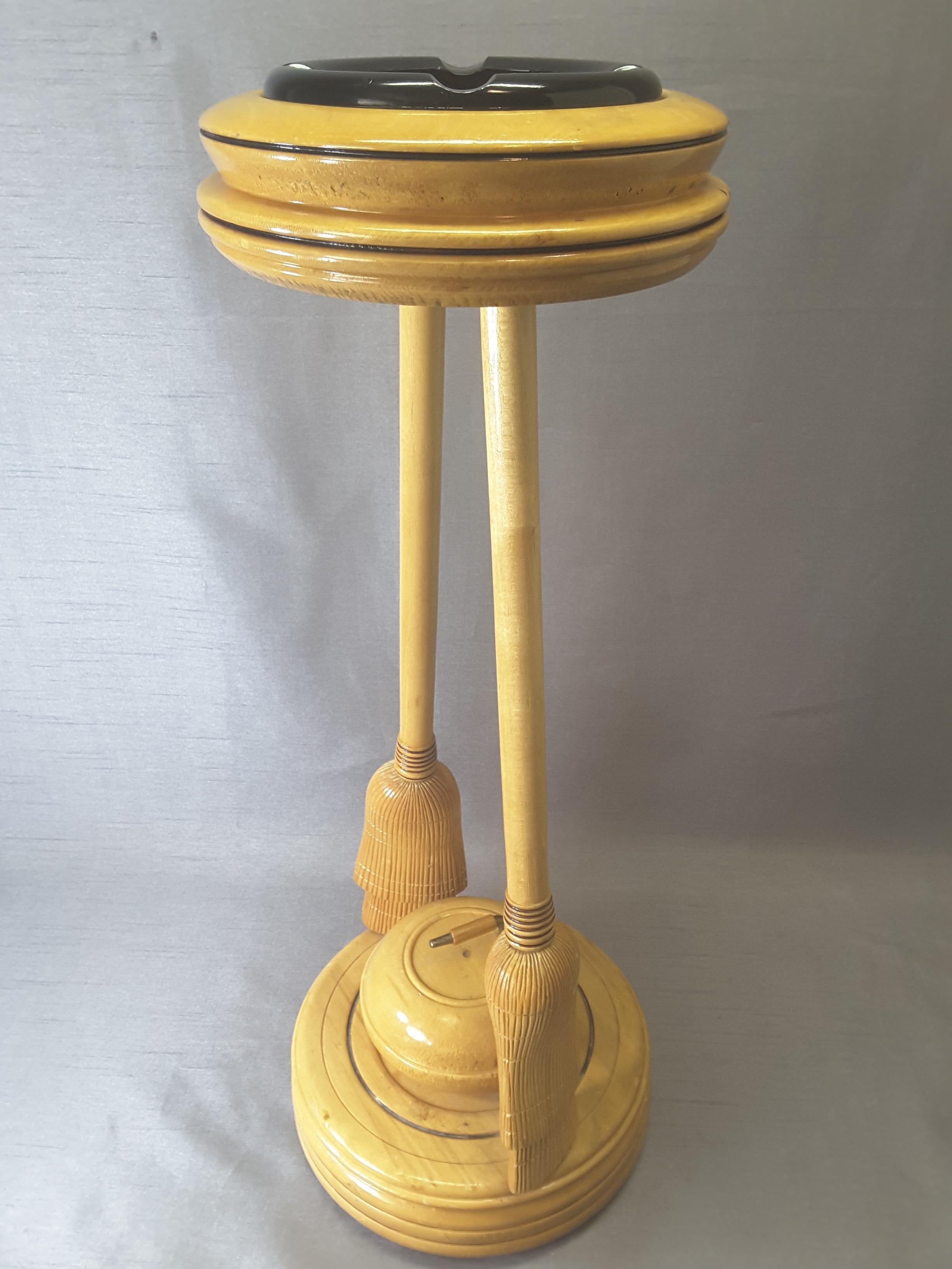 Curling Bonspiel trophy stand-up ashtray, early 1960s, The stand is maple with two curling brooms holding the top ashtray with the base mounted on a turned base and centered by a curling stone. The stand is made of maple, with a black glass ashtray.
