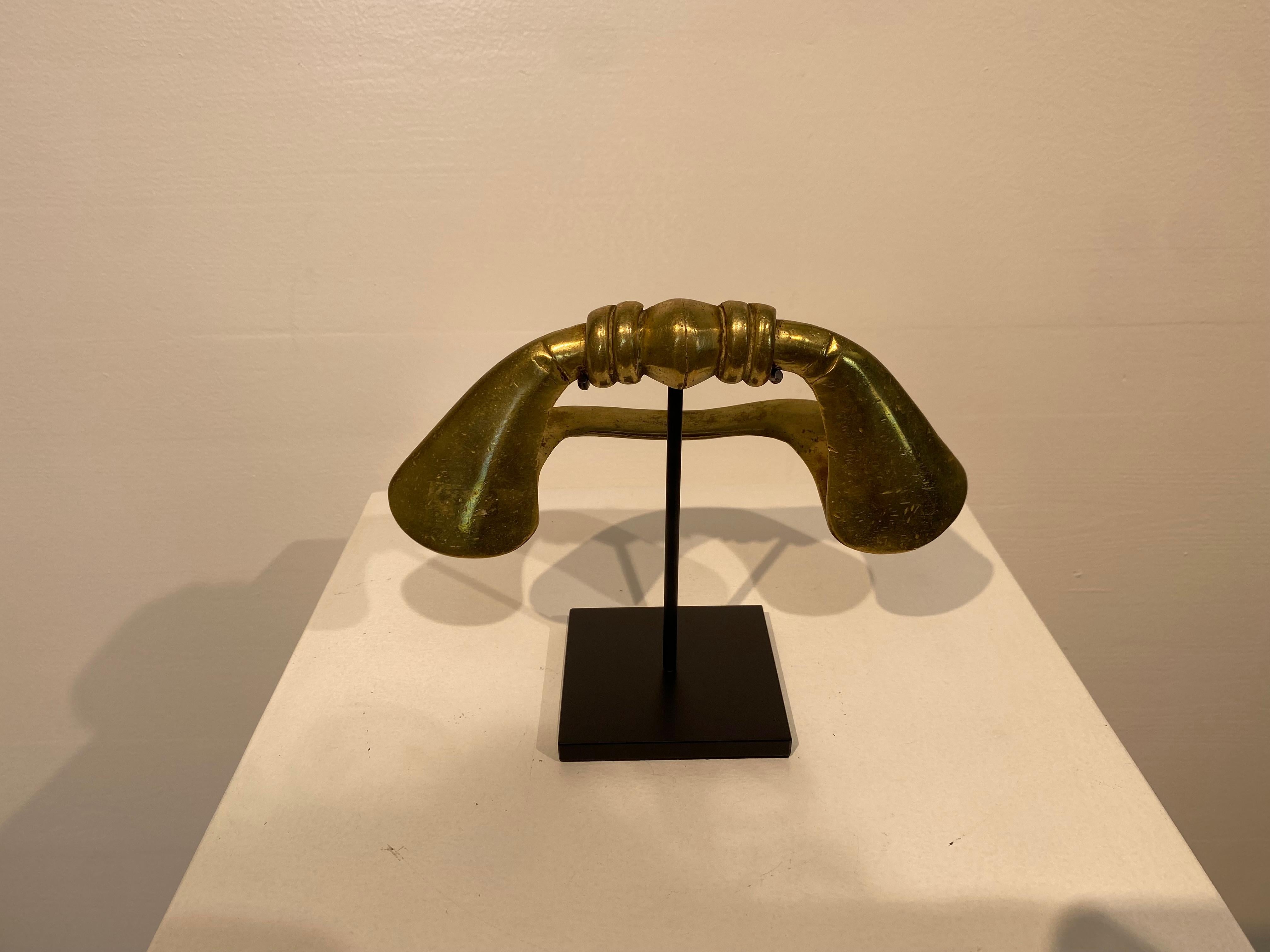 Moneta africana della Costa d'Avorio, tribù dei Senufo,
si tratta di una Cavigliera o Moneta da Barca, utilizzata come oggetto di scambio,
in ottone, con una patina calda e lucente,
un oggetto molto decorativo,
montato su una base di metallo