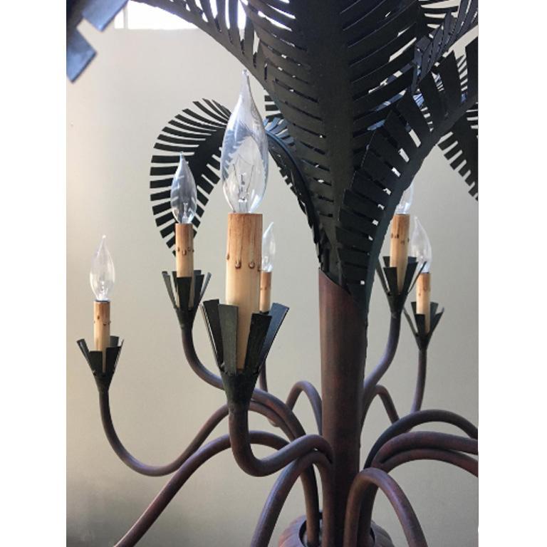 Striking sculptural chandelier by Currey & Co. features tole metal palm fronds and twelve arms. Perfect statement piece for Hollywood Regency, Old Florida, Palm Beach, Mid-Century Modern, Tropical, Coastal decor, and more. Good condition with
