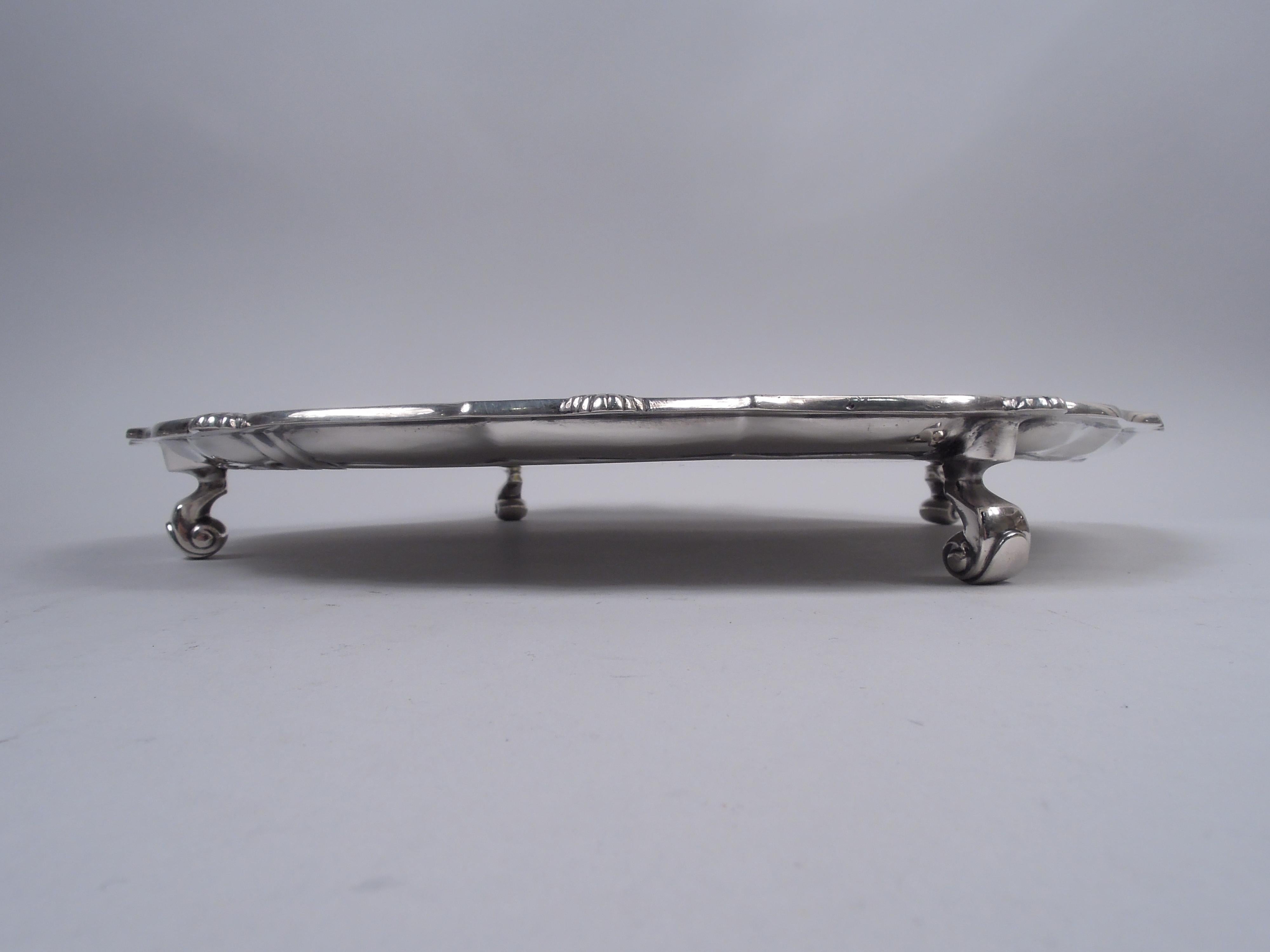 Traditional Georgian sterling silver salver. Made by Currier & Roby in New York, ca 1920. Molded scroll rim interspersed with scallop shells. Four capped volute-scroll supports. Fully marked including maker’s stamp and no. 2442. Weight: 40.5 troy