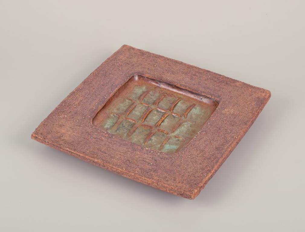 Curt Magnus Addin (1931-2007), Swedish ceramist. Own studio.
Square ceramic dish in a modernist style. Chamotte clay.
1970s.
Stamped and signed.
In perfect condition.
Dimensions: D 26.0 cm x H 3.2 cm.