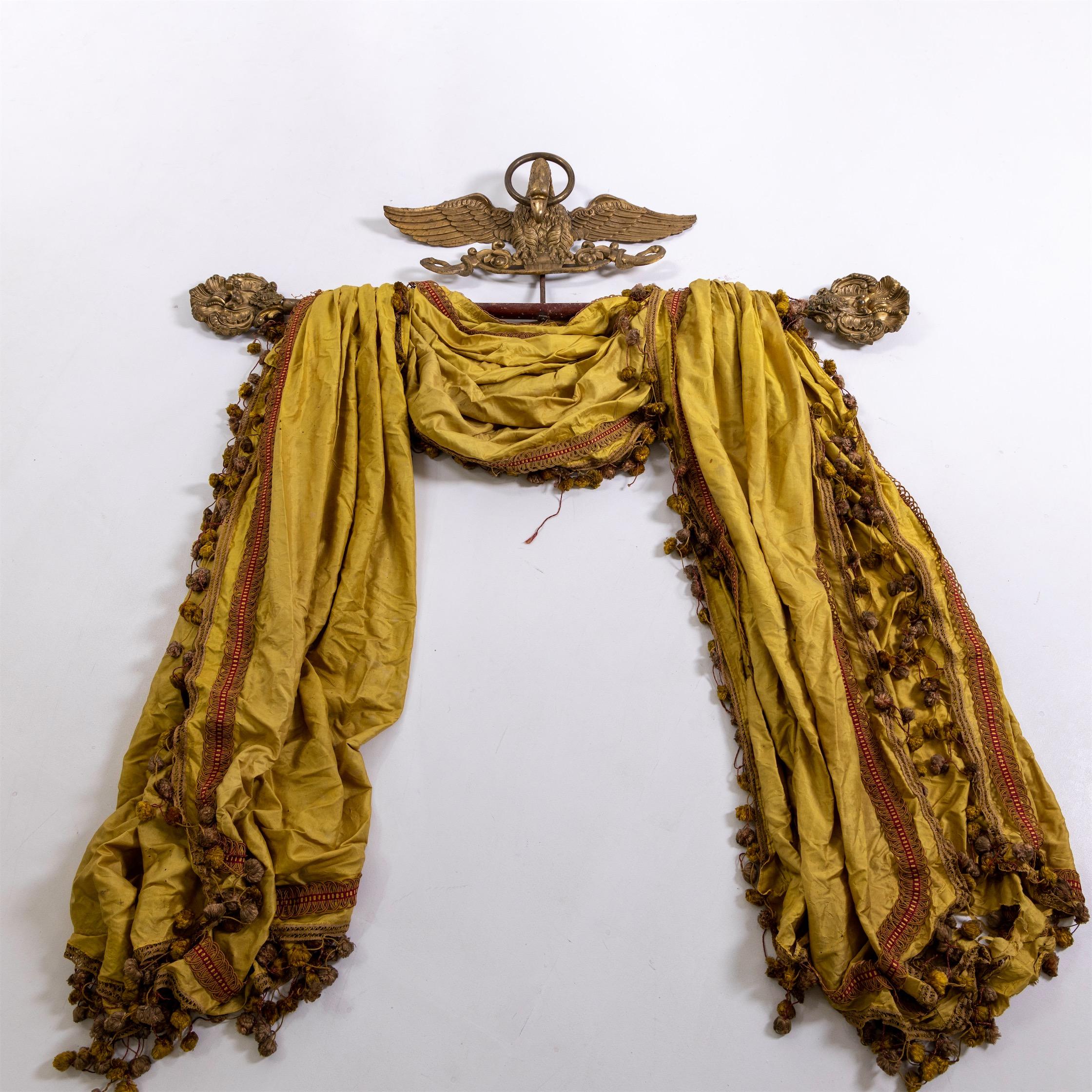 Curtain rod with crowning eagle and golden silk scarf.