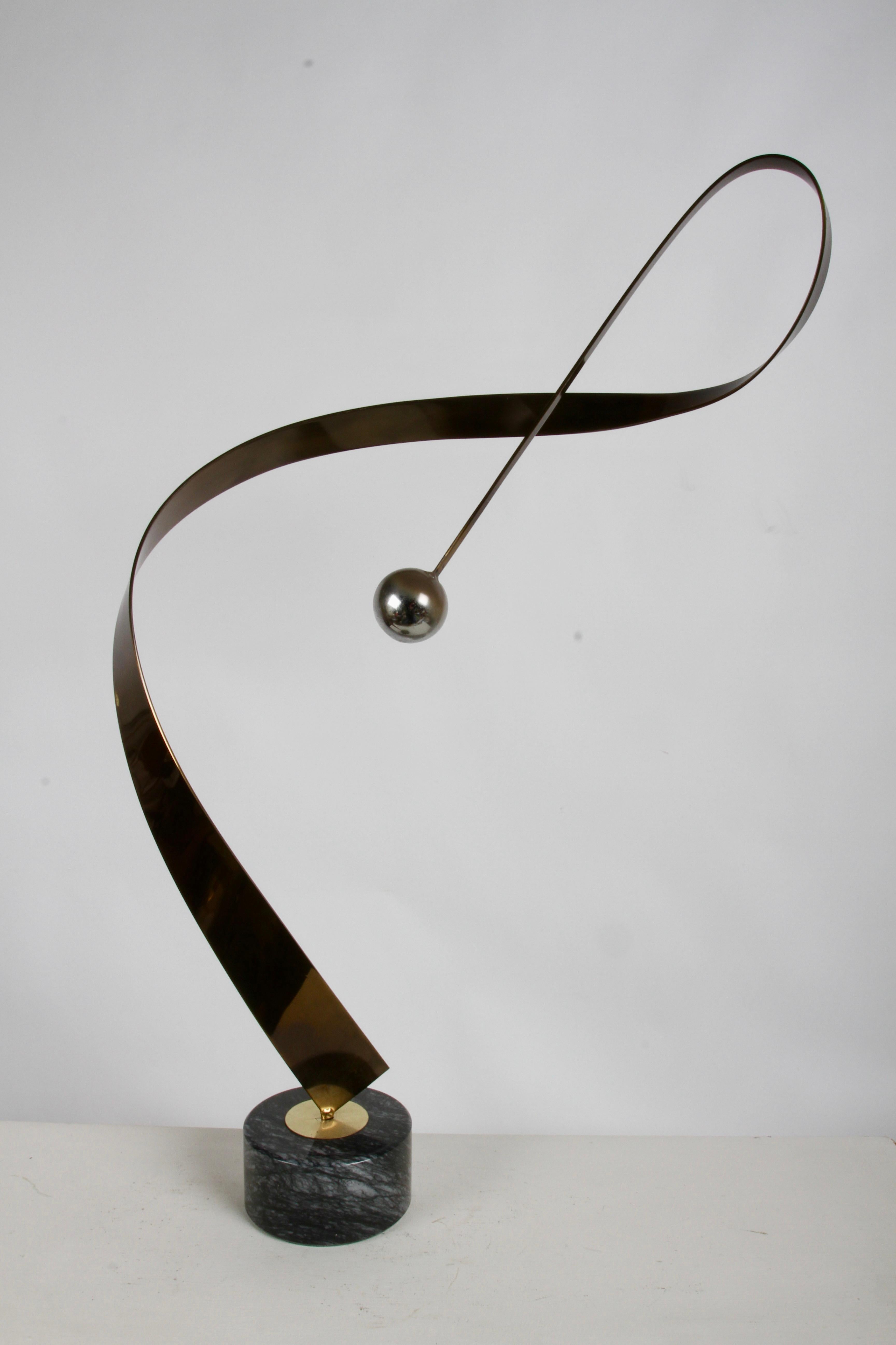 Scultura astratta da tavolo a forma di nastro cinetico in ottone di Curtis Jeré degli anni '80 circa, con sfera cromata su base rotonda in marmo nero. Manca la decalcomania Artisan House - C.Jeré sul fondo, come la versione cromata che ho elencato. 