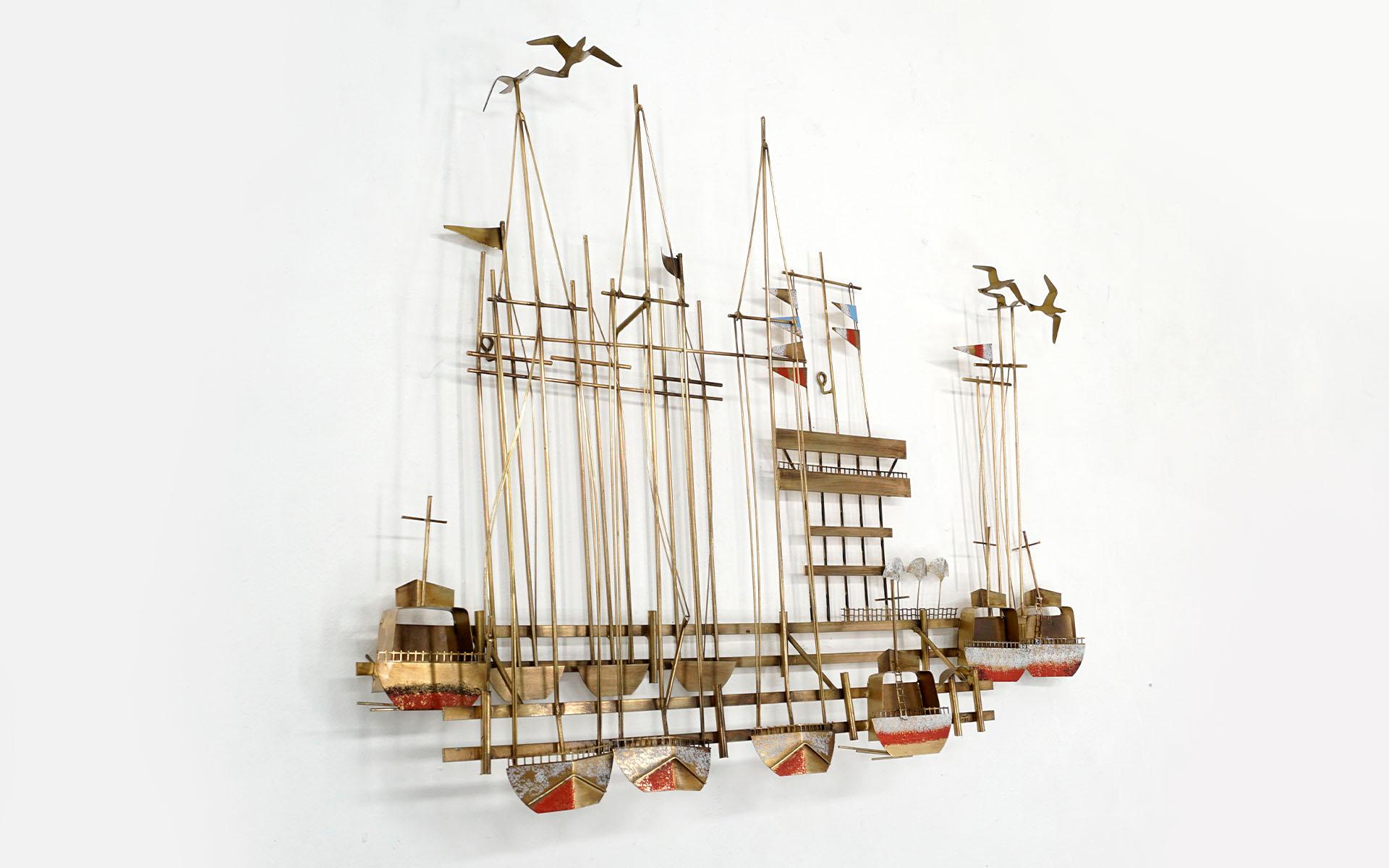 Brass and metal wall sculpture by Curtis Jere. Scene of docked sailboats with multicolor flags and flying sea gulls. Patinated brass and metal in very good condition. Ready to Hang.