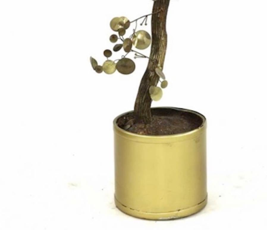 A mid-century contemporary Curtis Jere brass sculpture of a tree.

The tree features brass metal flamed patinated leaves and stems mounted on a gilded natural wooden tree trunk.  

Sculpture is mounted in a brushed brass planter with faux soil that