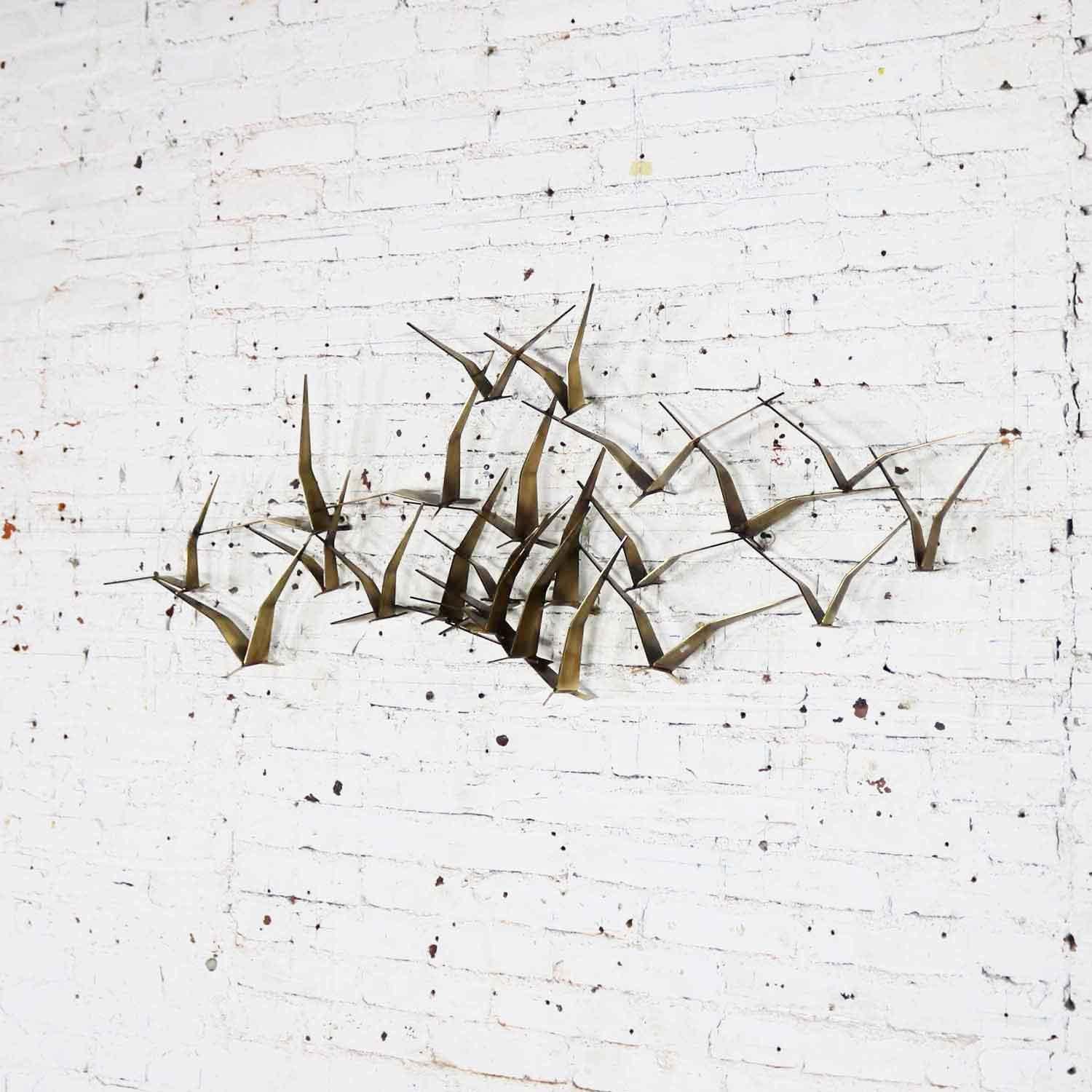 Handsome wall hanging sculpture in gold tone metal of a flock of flying birds or seagulls by Curtis Jere. This piece is in fabulous vintage condition. Signed C. Jere 1989. 

This fantastic wall sculpture looks fabulous from every direction! It