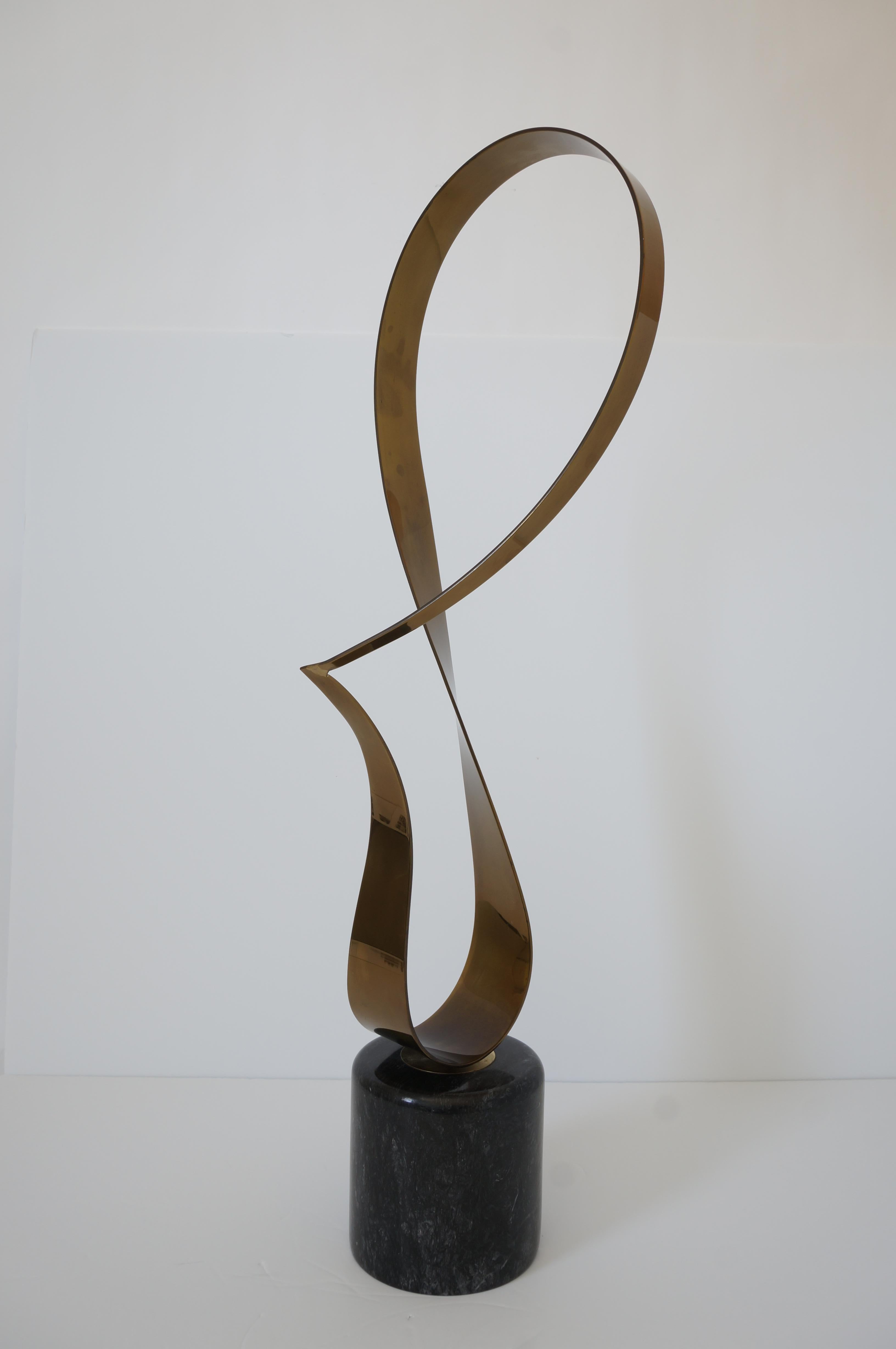 This stylish patinated brass free-form ribbon sculpture dates to 1984 and was created by Curtis Jere and produced by Artisan House of California. 

Note: Base measures 6.13