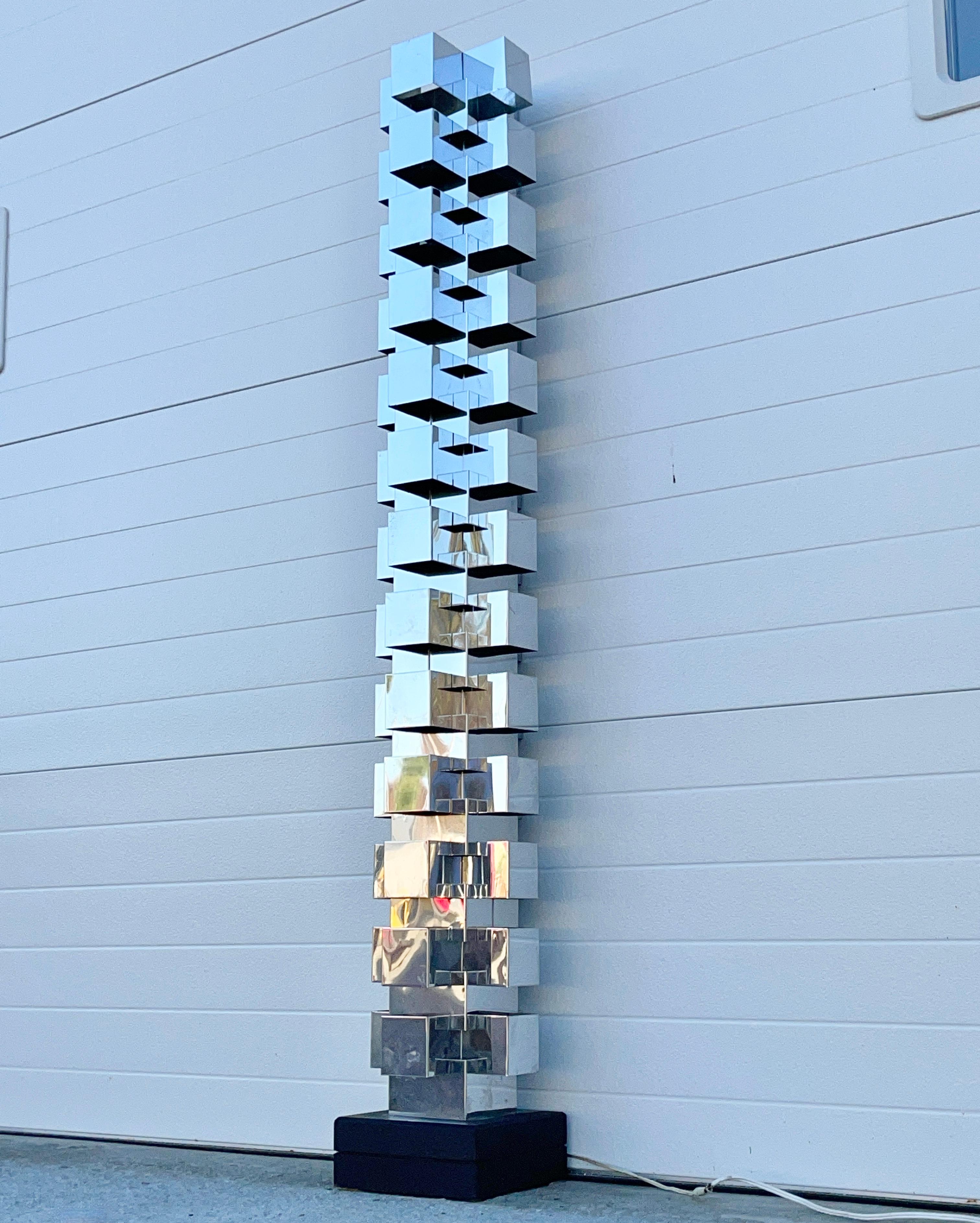 Very clean and dramatic architectural floor lamp comprised of multiple segments of mirror polished stainless steel sheet that have been cut and formed with precision into geometric building blocks that together form a single tower out of multiple