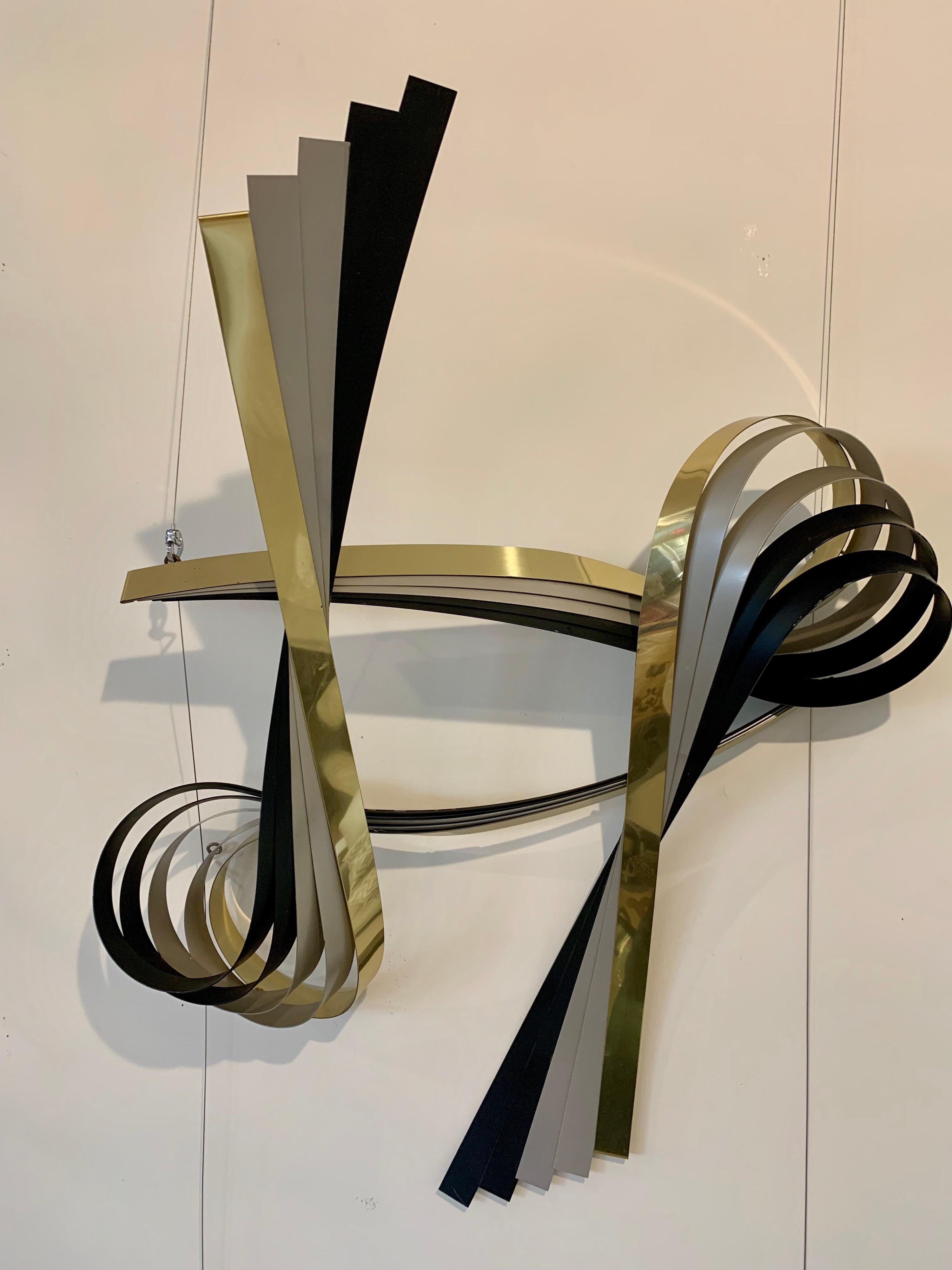 Stunning 1980s hanging wall sculpture by Curtis Jere depicting a large flowing ribbon in brass and black chrome. Ready to hang and can be hung either vertically or horizontally.