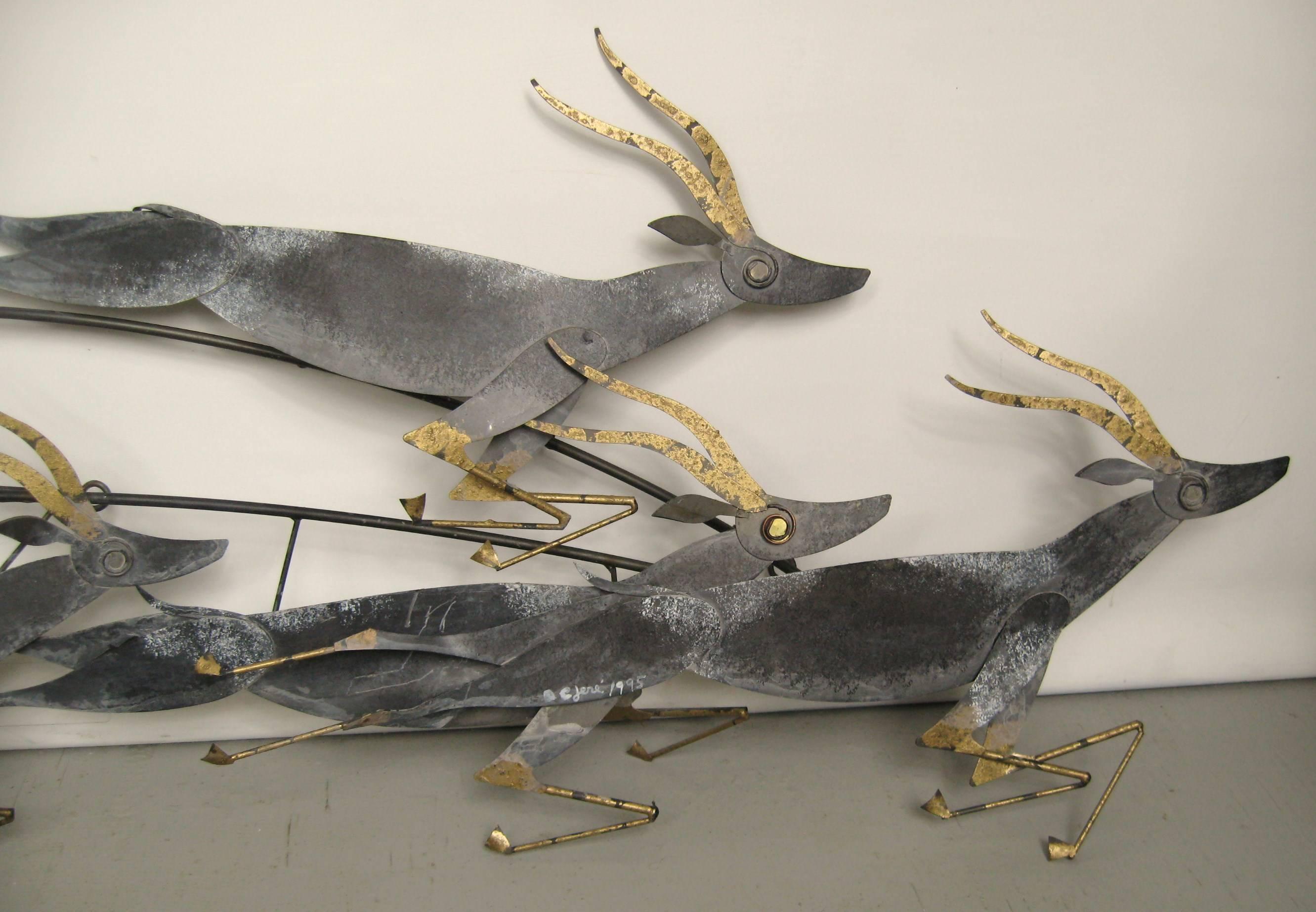 Tin with gold highlights, a wall-mounted sculpture of a herd of running gazelles. Wall sculpture designed by Curtis Jere. Each gazelle is about 24 in.
 