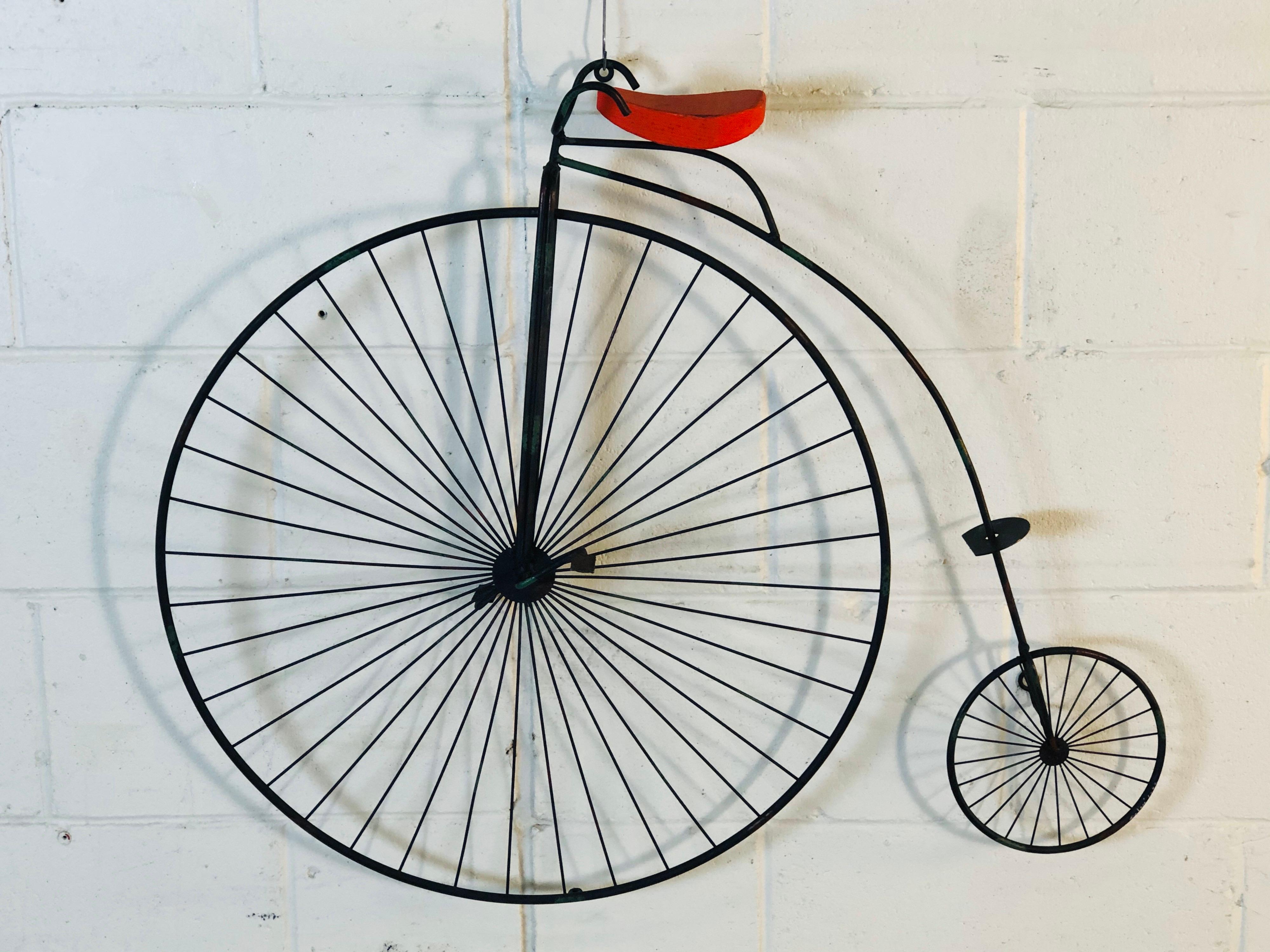 Vintage Curtis Jere signed iron penny farthing bicycle wall sculpture with a red seat. Signed and dated 1982.