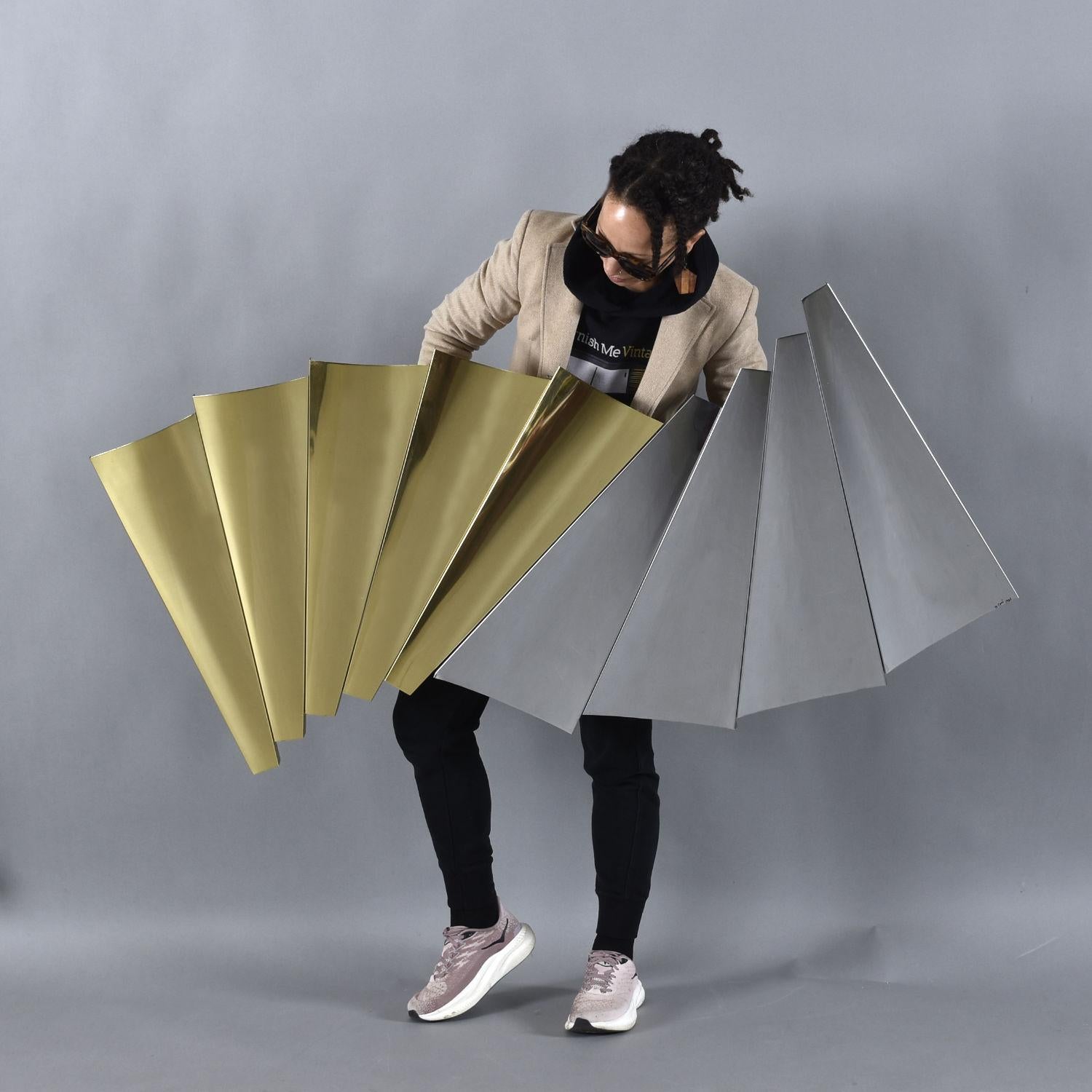 Curtis Jere’s “Outfold” silver and gold metal sculpture will cast a wave of glamour across your wall. This glitzy wall sculpture features a pleated gold and silver/chrome side. Each of these halves are actually independent pieces that are joined
