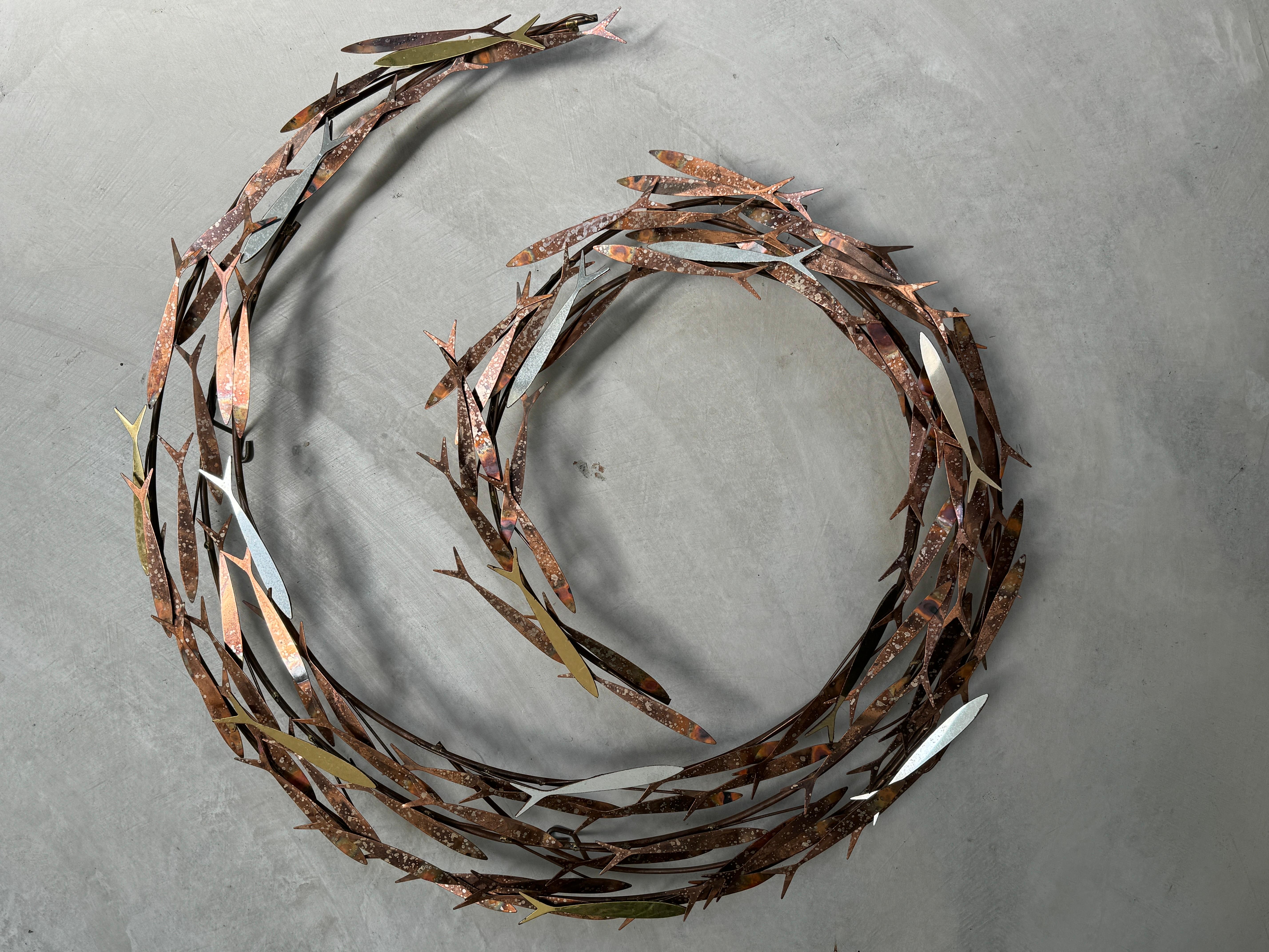 Jere mixed metal wall sculpture depicting school of minnows swimming in a circle. The wall sculpture is signed and dated. Swirling school of fish metal wall sculpture with highly patina brass finish. This will go great in your Mid Century or post