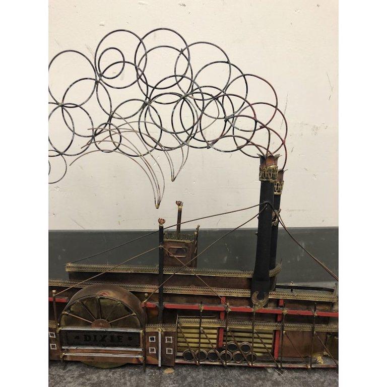 A carefully and creatively crafted model steamboat! Crafted and signed by Curtis Jere. Every detail from cargo barrels, to whips of smoke complete the trip down memory lane, or the Great Mississippi. This piece sits upright or can be hung on your