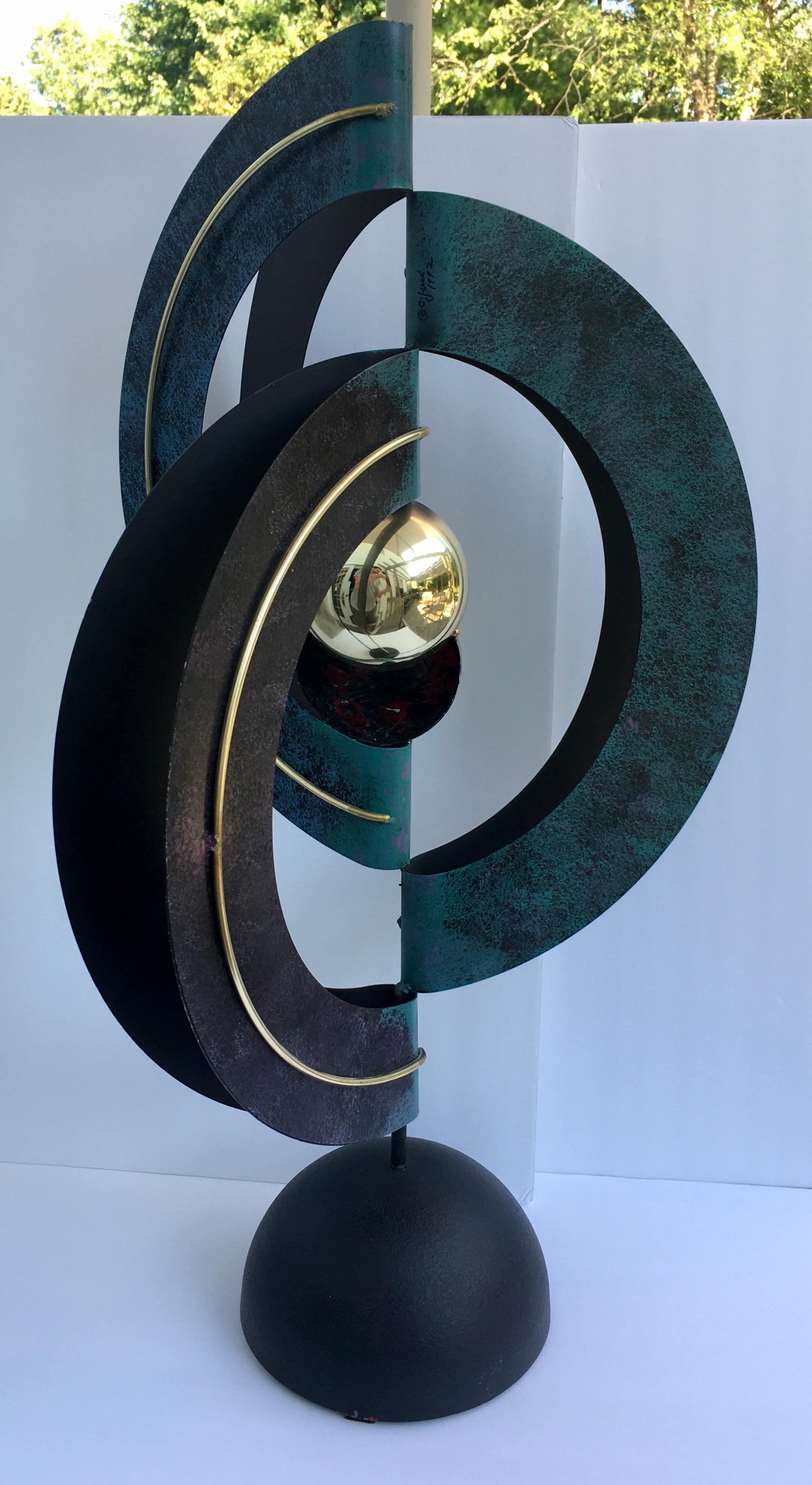 Curtis Jere table sculpture. This sculptural piece of art is composed of three polychrome enamel decorated and folded sheet metal circles centering a split gold-tone sphere and raised on a domed metal base, signed and dated “C Jere 1992”,

Late