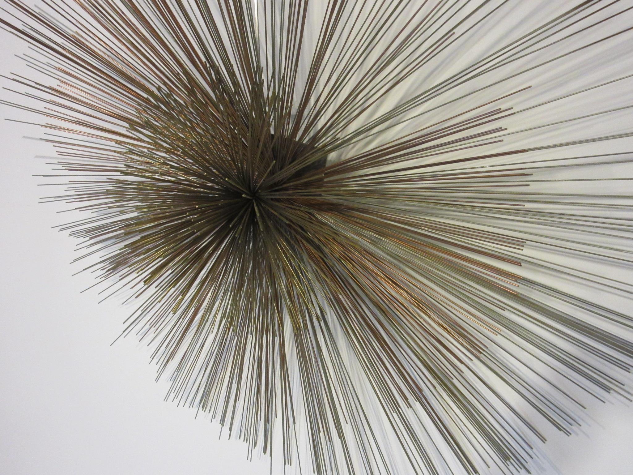 A large Jere sunburst wall sculpture with a wire pom forming the center surrounded by large wire forms in stainless steel, brass and copper. Manufactured by Curtis Jere, California.
