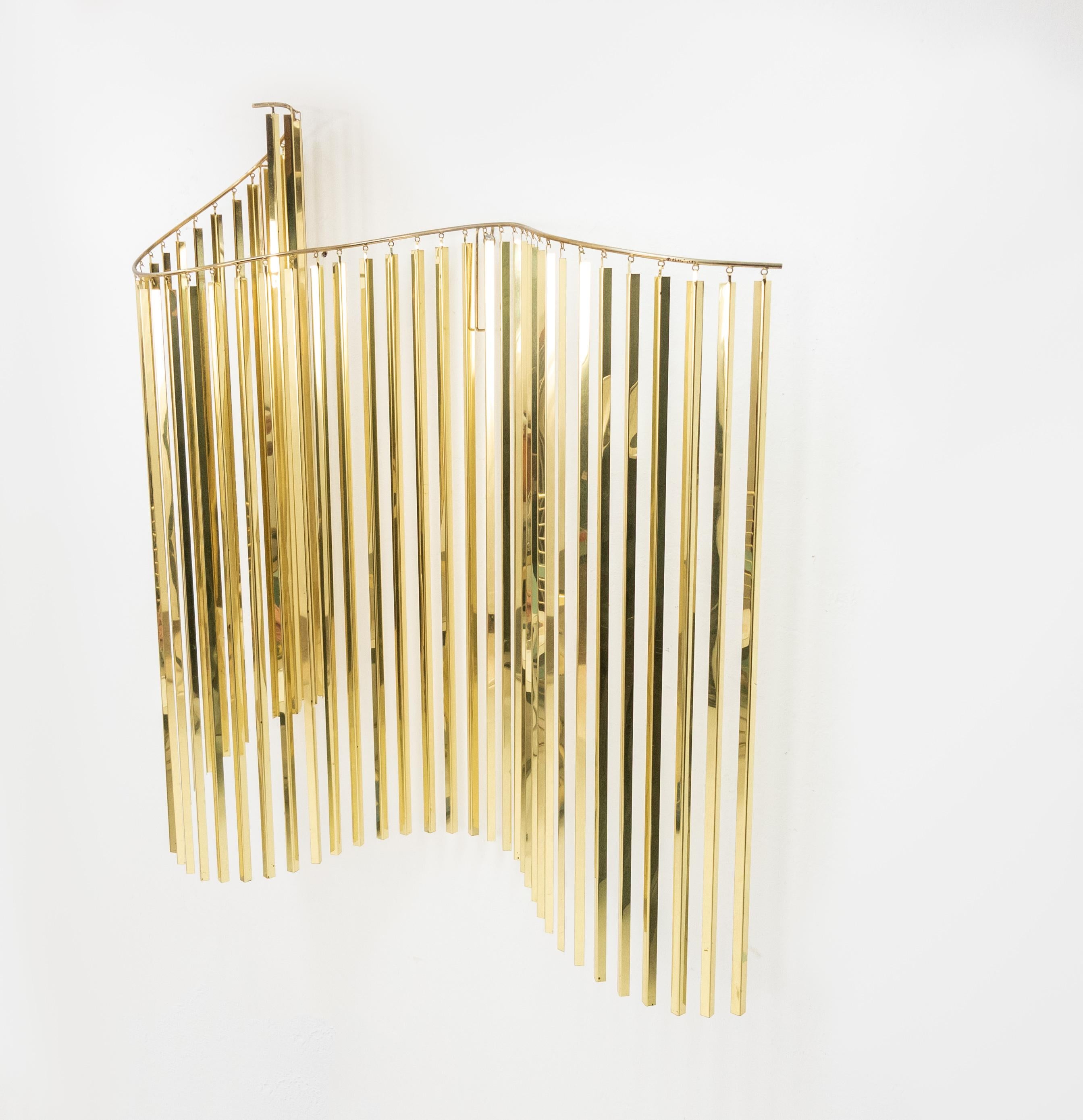 Large-scale brass C. Jeré for Artisan House. Wave like sculpture. It is made up of 44 V-shaped reflective brass strips that dangle from the curved hanging rod resembling a wave in motion. There are two wall mounts on the hanging rod that will