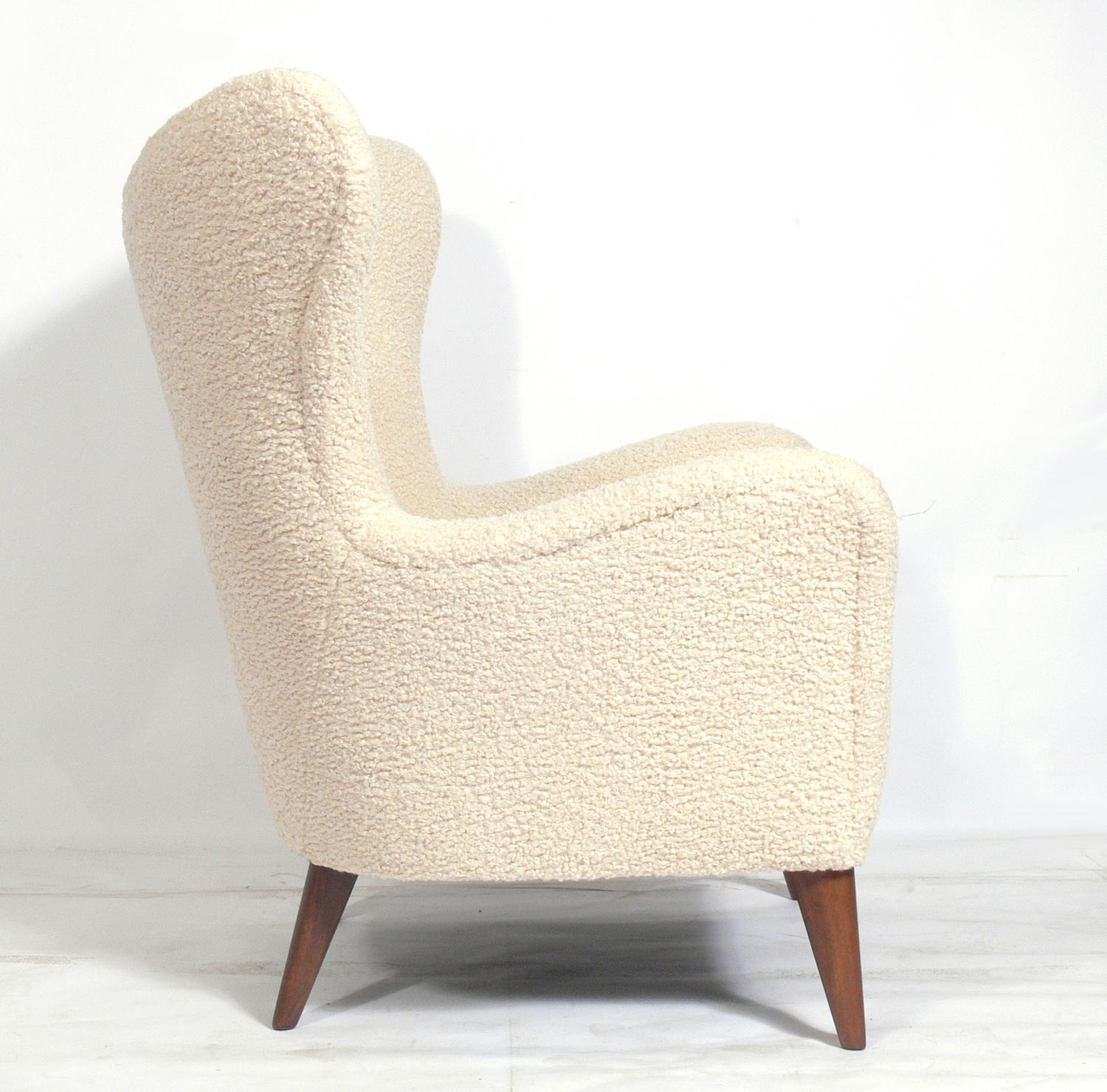 Curvaceous Danish lounge chair, Denmark, circa 1960s. It has been completely restored with the walnut legs refinished and reupholstered in an ivory color faux shearling upholstery. Super plush and soft.