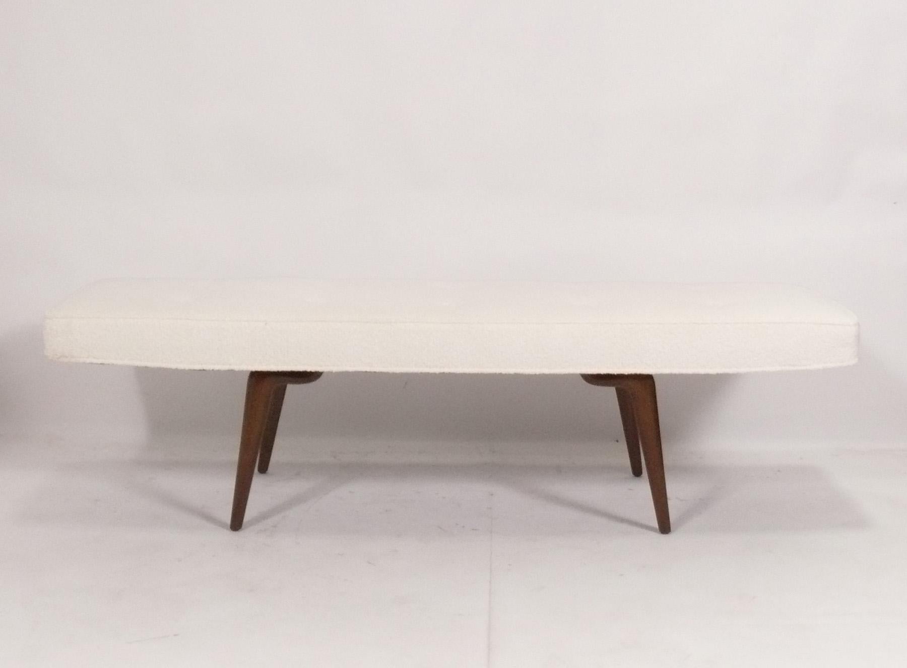 Curvaceous Mid Century Walnut Bench, believed to be Italian, circa 1960s. It has recently been fully restored with the walnut legs refinished and the cushion reupholstered in an ivory color boucle fabric with new foam inside.
