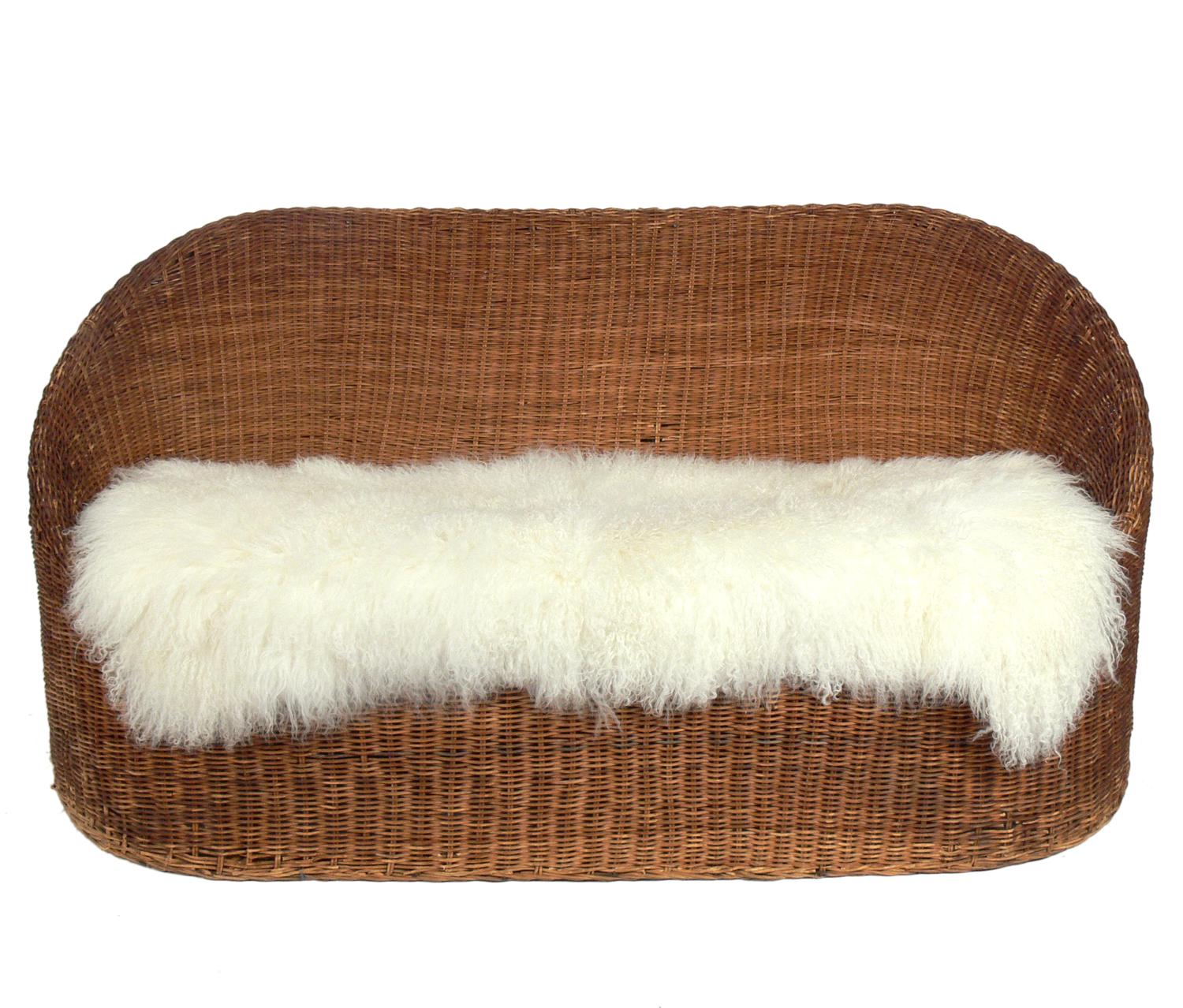 Curvaceous wicker settee, attributed to Isamu Kenmochi, circa 1960s. It has a new cushion in an ivory color herringbone fabric and includes the Mongolian sheepskin throw. The wicker retains it's warm original patina.