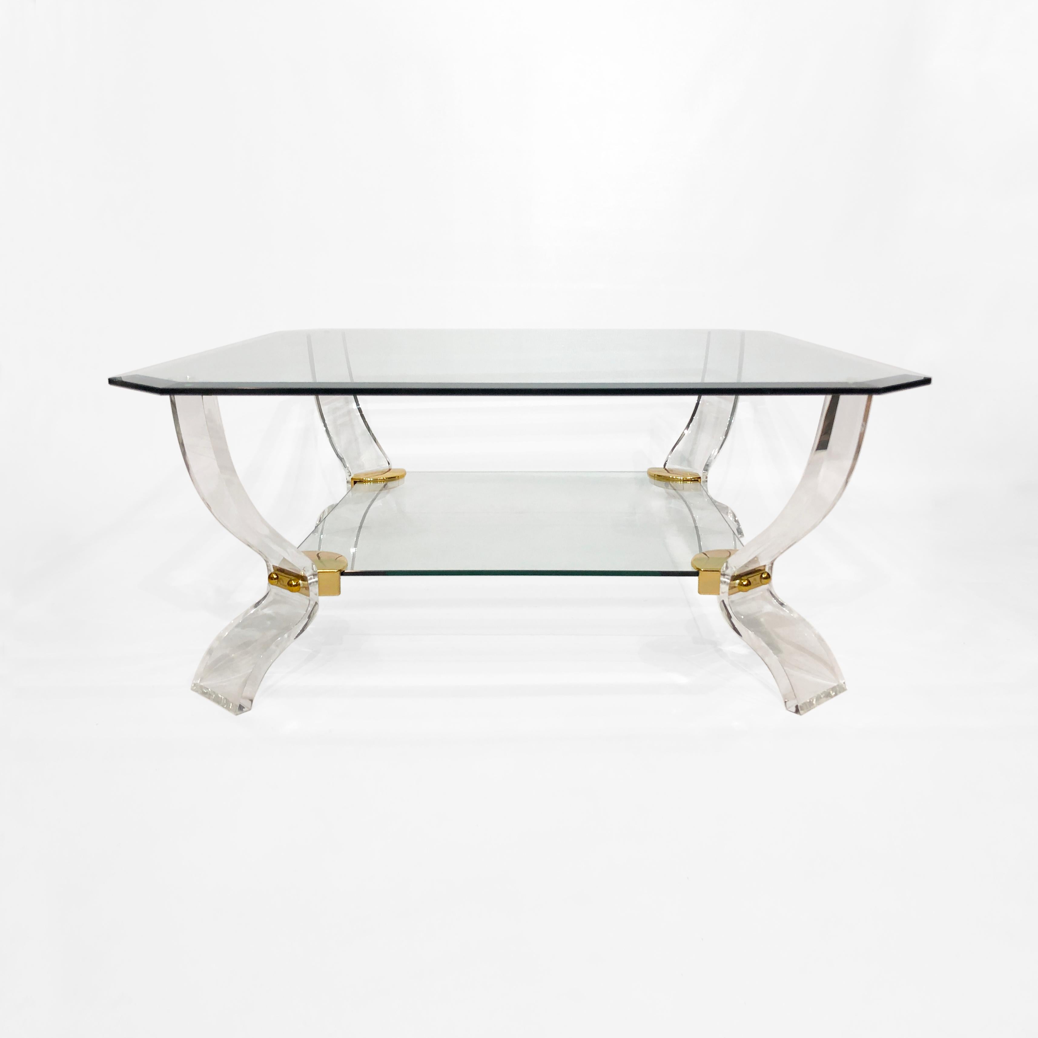 An elegant 1980s octagonal-square lucite and glass tiered coffee table by Curvasa Muebles, and very much in the style of Charles Hollis Jones. The thick octagonal bevelled glass top is supported on four hourglass-shaped lucite feet, with gold