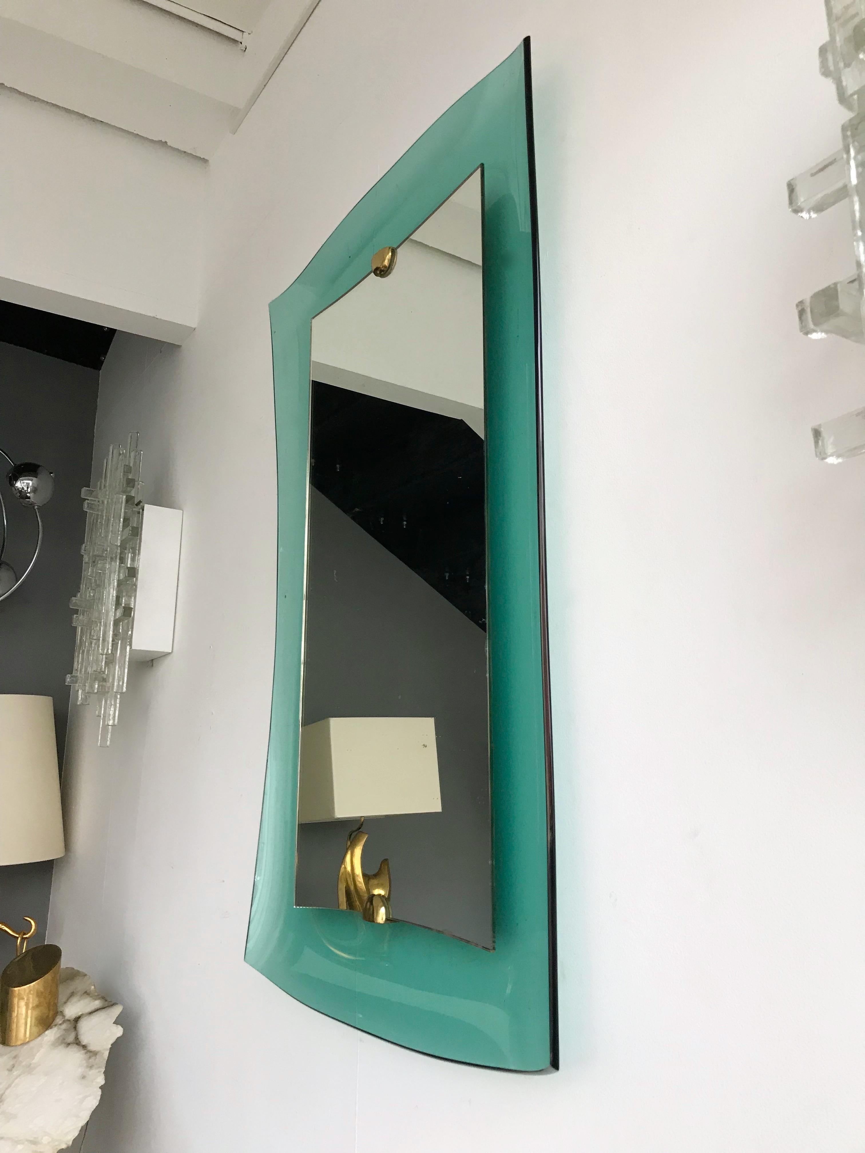 Rare wall mirror in blue turquoise green curve glass, brass elements by the famous crystal and glass manufacture Cristal Art who was the concurrent of Fontana Arte at the same period. The mirror was presented during the Milan furniture fair in 1962