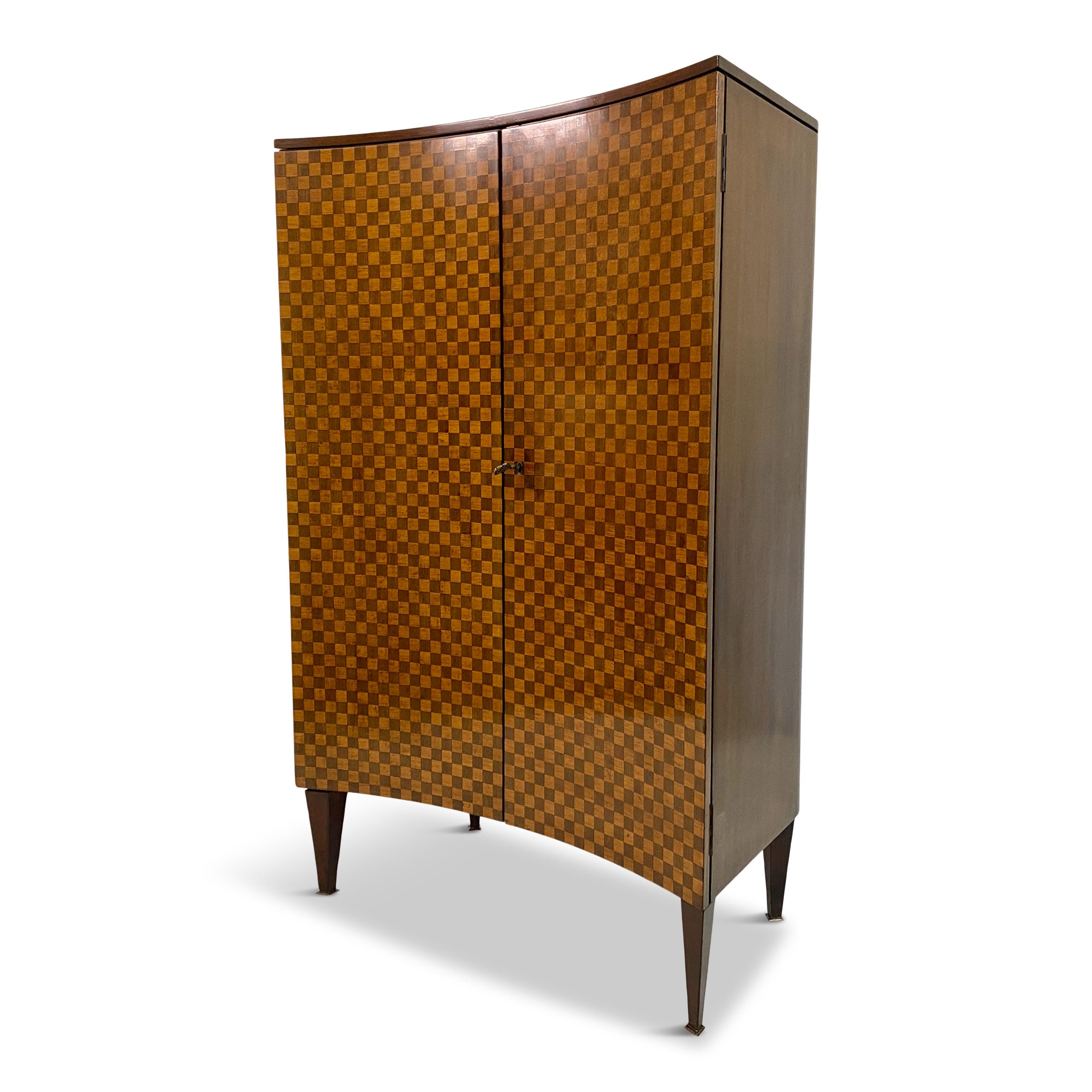 Drinks cabinet.

Chequerboard front consisting of alternating maple and ebony squares showing an amazing amount of work, skill and quality.

Brass quadrilateral feet.

Finished curved back.

Two glass shelves and one pull out glass shelf with brass