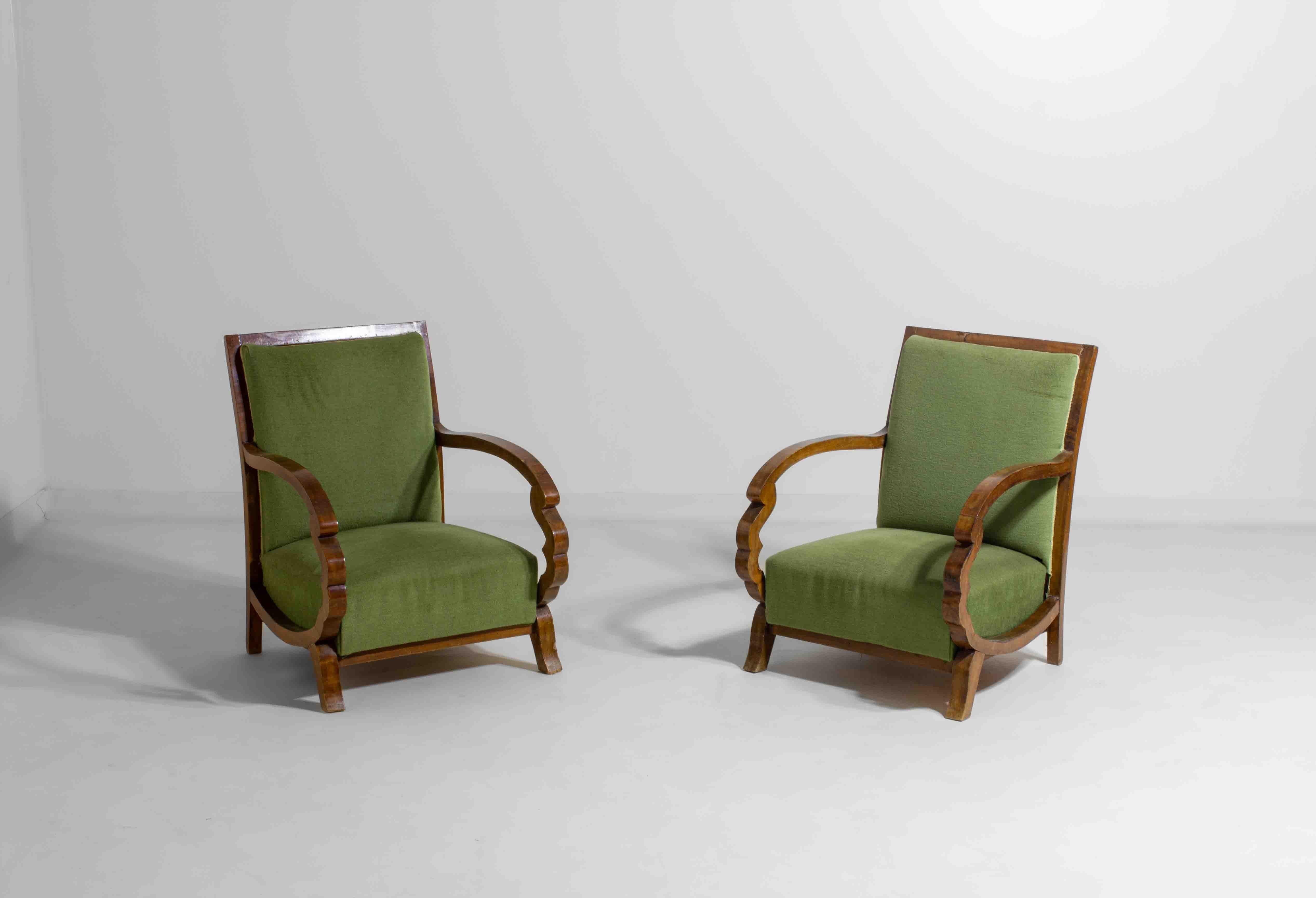 Elegant pair of Art Deco lounge chairs with matching ottomans, made in the 1930s. The solid wood frames feature curved armrests and subtle carving, typical for the period. The green upholstery adds a fresh, timeless look and offers a soft and