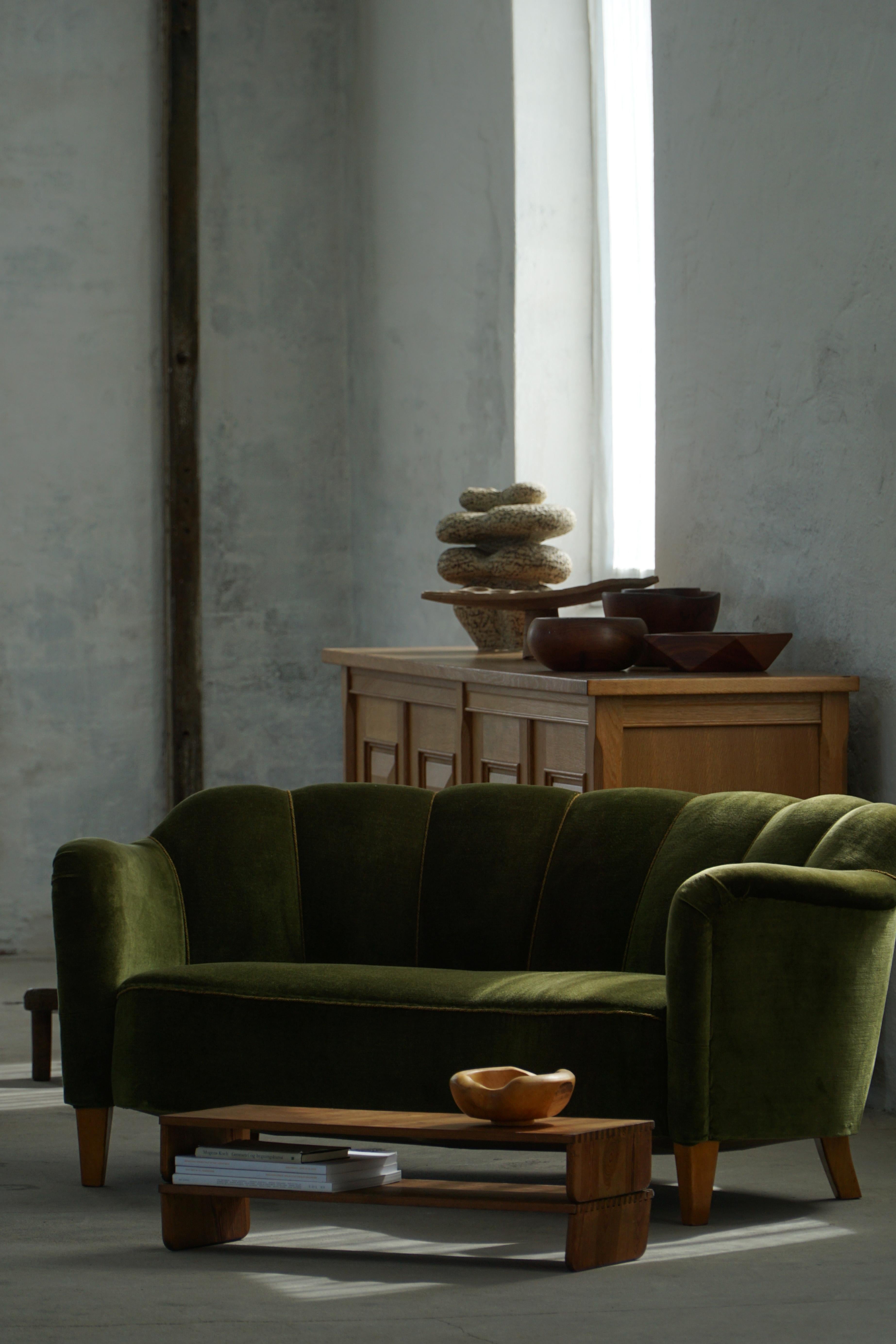 This distinctive sofa, upholstered in rich green velour, exemplifies the refined artistry of a Swedish cabinetmaker from the 1940s Art Deco era. It exudes both charm and sophistication, merging the plush texture of velour with the geometric grace of
