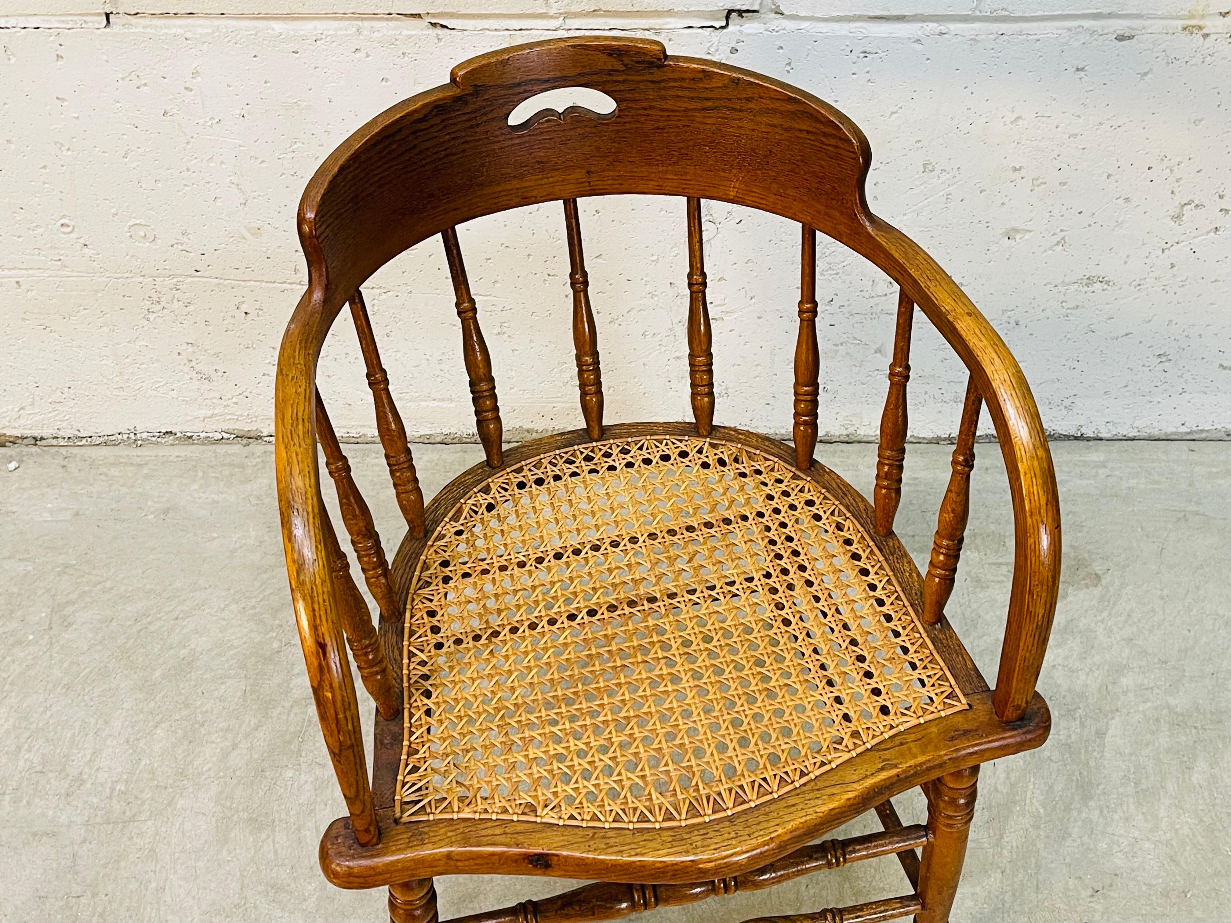 Vintage 1930s oak wood barrel style chair with a curved back and cane seat. Chair is sturdy and the cane is in excellent condition. Nice original patina to the wood. No marks.