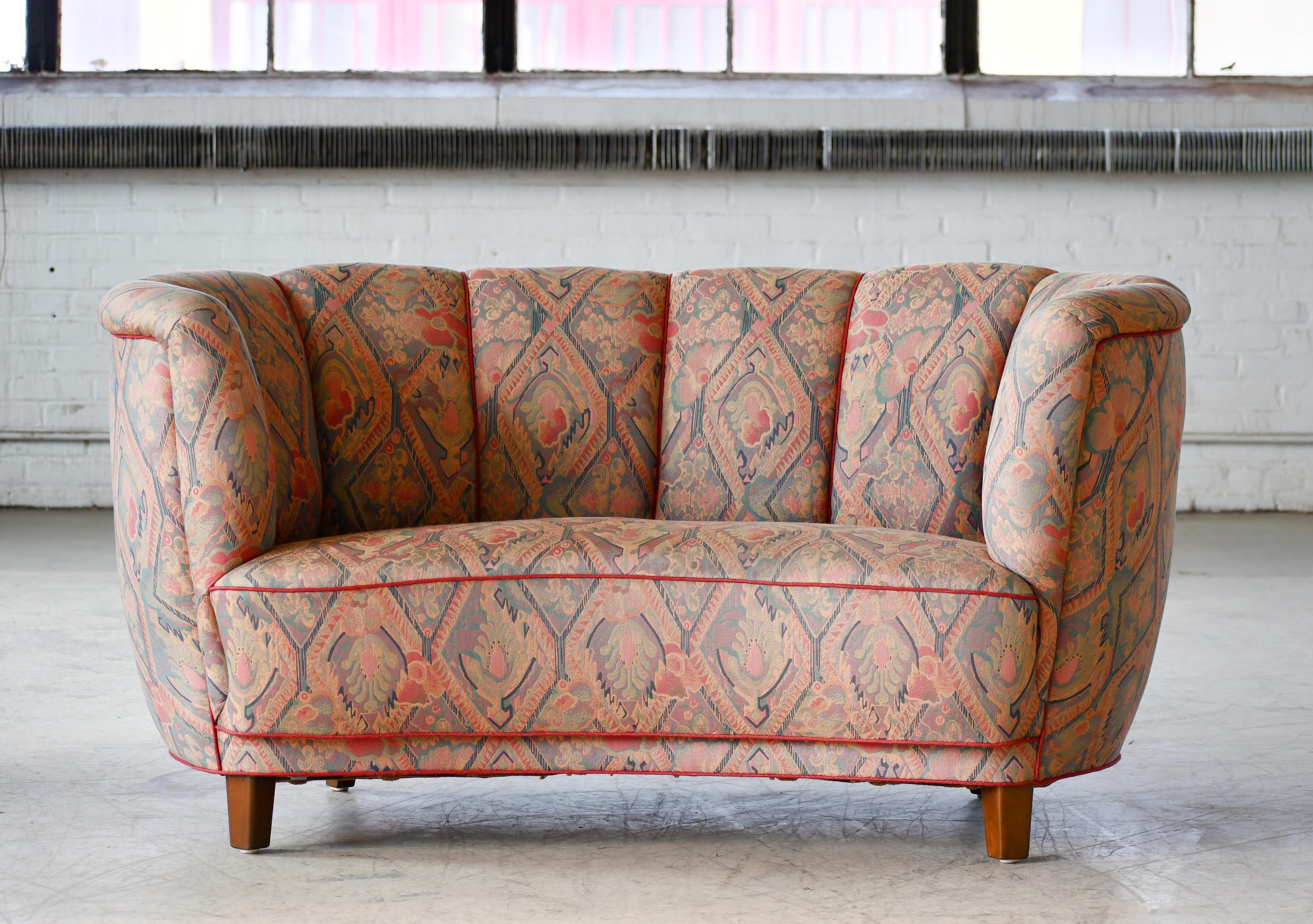 Viggo Boesen style banana shaped or curved Loveseat made in Denmark, around late 1930s or early 1940s. This small sofa will make a strong statement in any room. Beautiful round voluptuous lines and solid thick legs. The original fabric is still