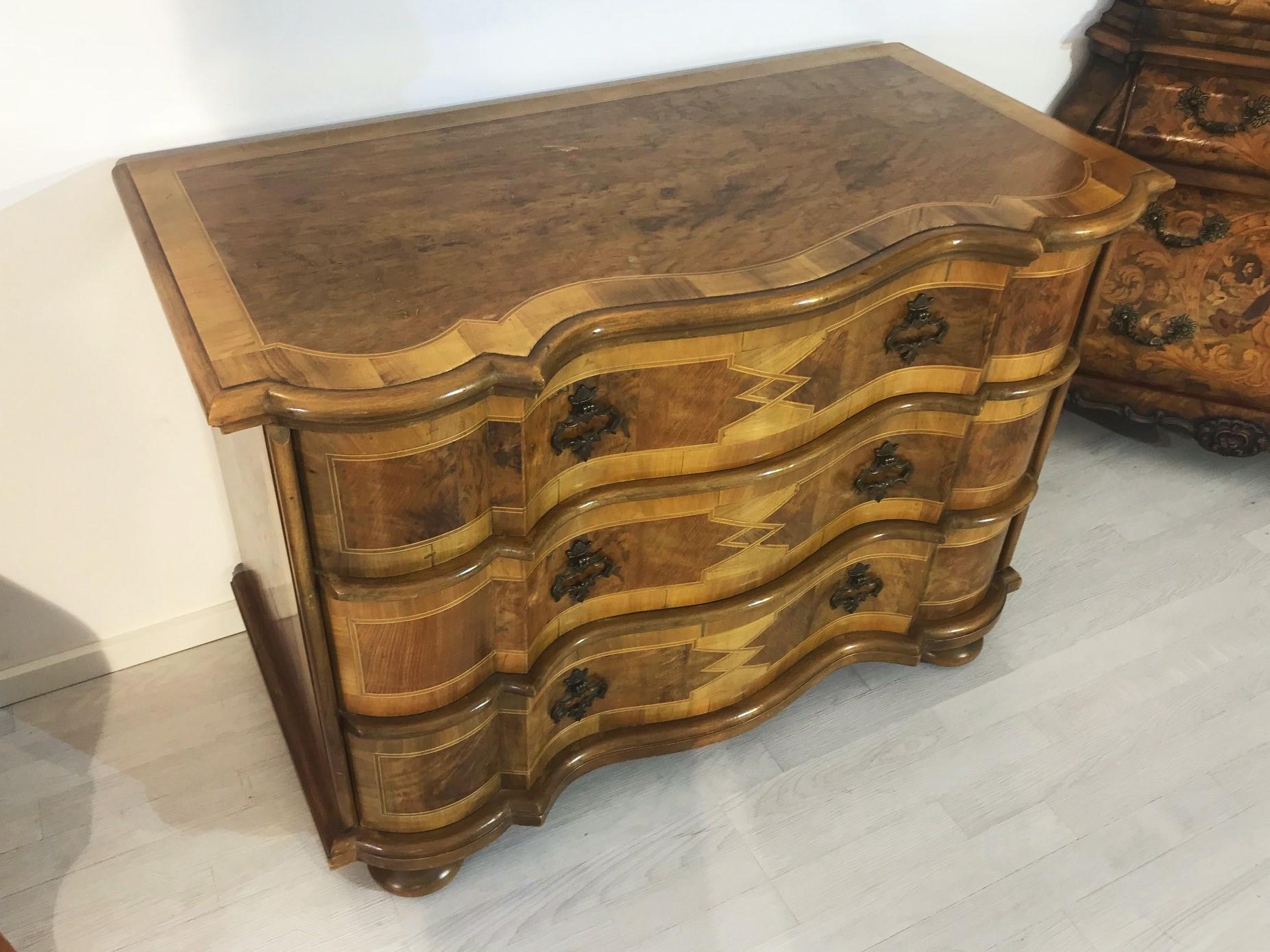 Curved baroque style chest of drawers. The high quality piece of furniture was made in the 1970s in Germany and convinces with a typical Baroque style design and beautiful ornamentation within the walnut wood. On the drawers fronts you will find six