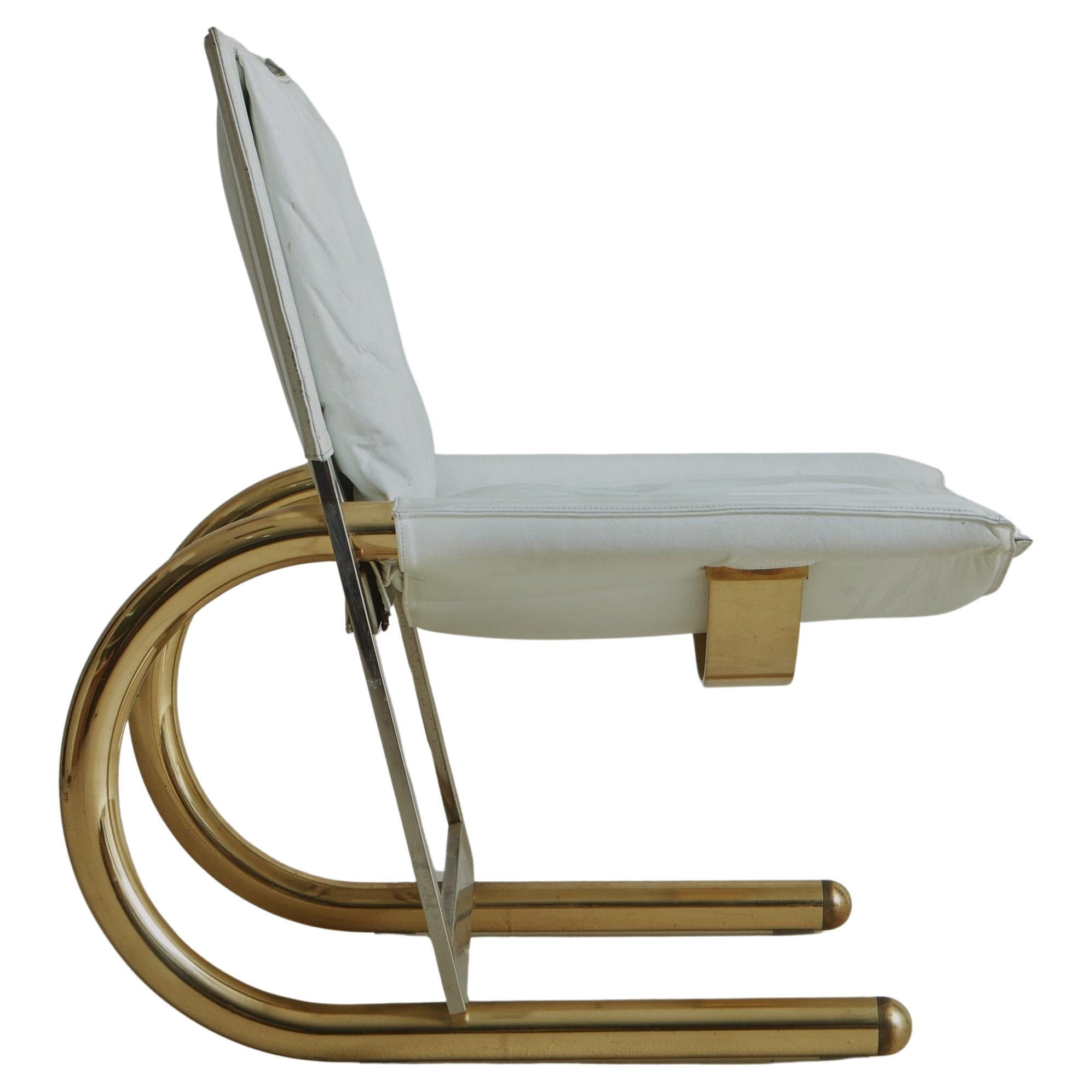 A 1970s Italian lounge chair featuring two dramatically curved tubular lacquered brass legs, which provide a striking contrast to the rest of the angular metal frame. Sourced in Northern Italy, this chair features a comfortable sling seat and back