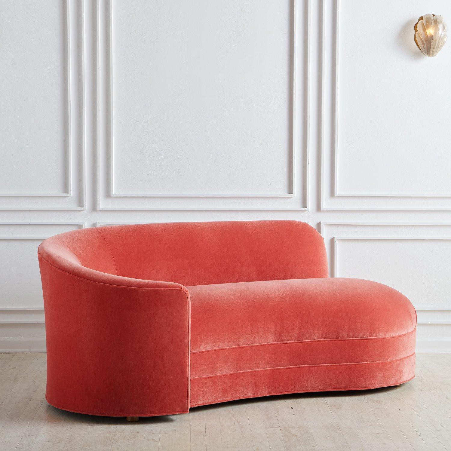 A beautiful curved chaise lounge featuring a rounded seat and curvaceous back which extends elegantly on the right side into an arm support. This piece was fully restored and reupholstered in a luxe pink velvet with single welt detailing. It sits