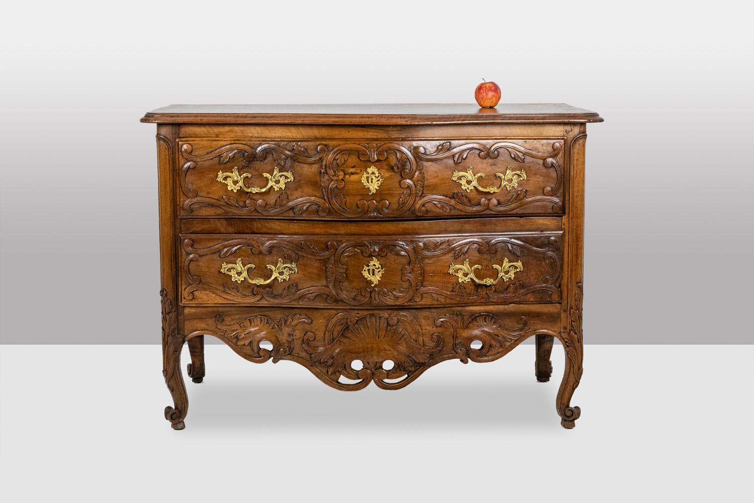 Curved chest of drawers known as a “nîmoise,” made of solid molded and carved walnut, with two drawers on the front.
Gilded bronze handles and keyholes.
18th-century French Provençal craftsmanship.
Dimensions: H 35.5 x W 50.8 x D 24.1