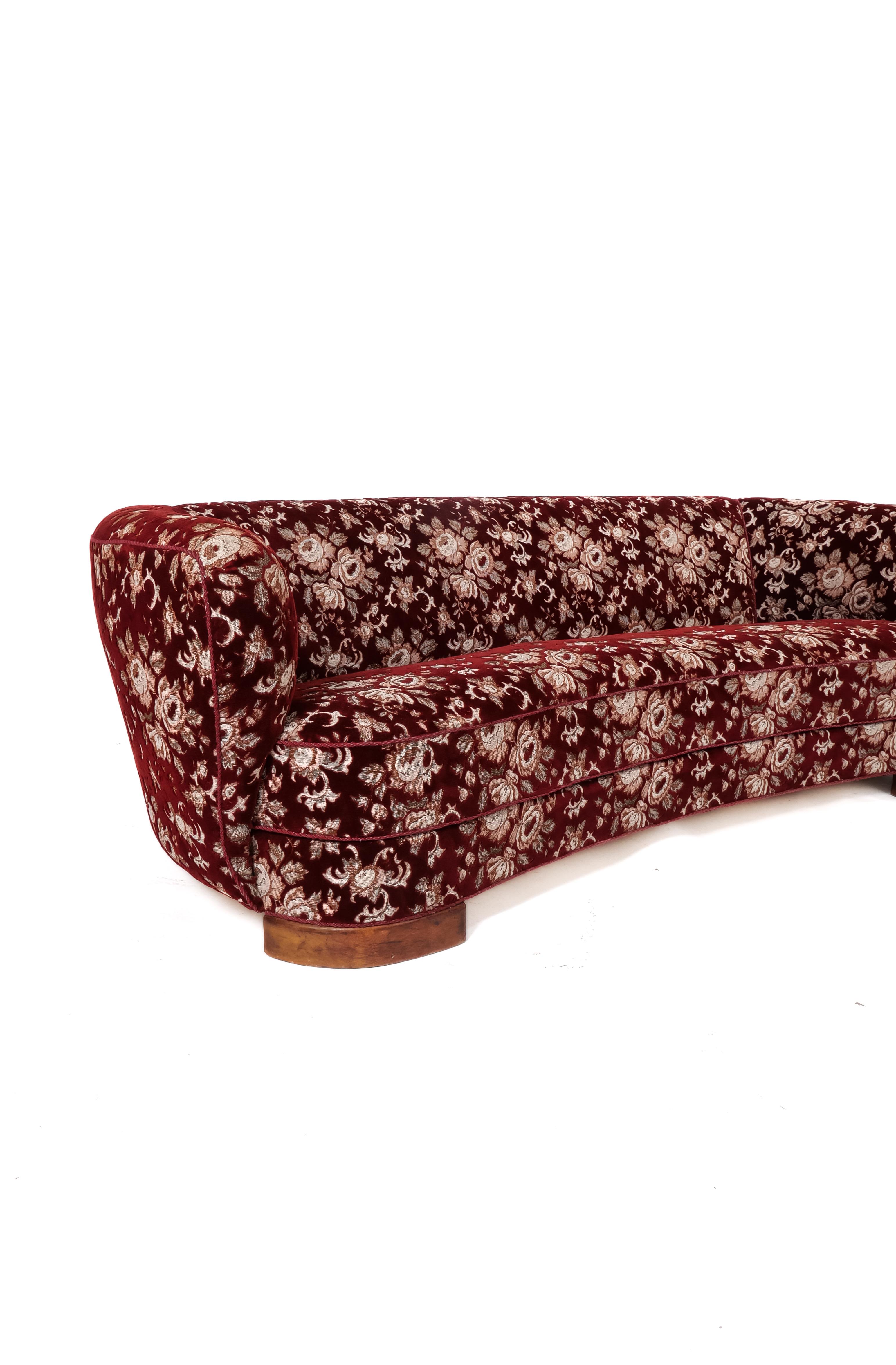 Fabulous floral velvet upholstery on this classic shape. Circa 1930s “Banana” sofa, elegantly curved  with deep seating area its low-slung back profile and strong arm lines create a dramatic statement. Stained beech legs. Upholstery in very good
