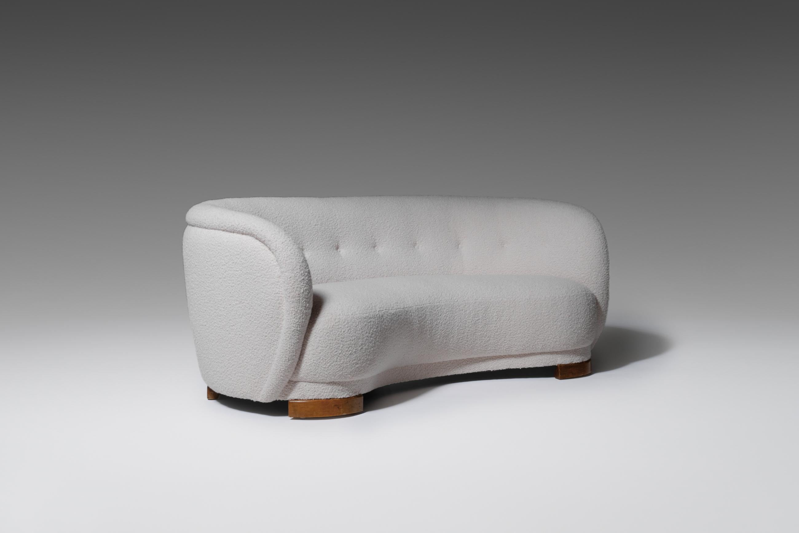Elegantly curved sofa fabricated in Denmark, 1930s. The sofa is reupholstered in a rich and modern bouclé, which make the eccentric round shapes stand out nicely and create excellent comfort. The beech sled legs and retracted knots make sure the