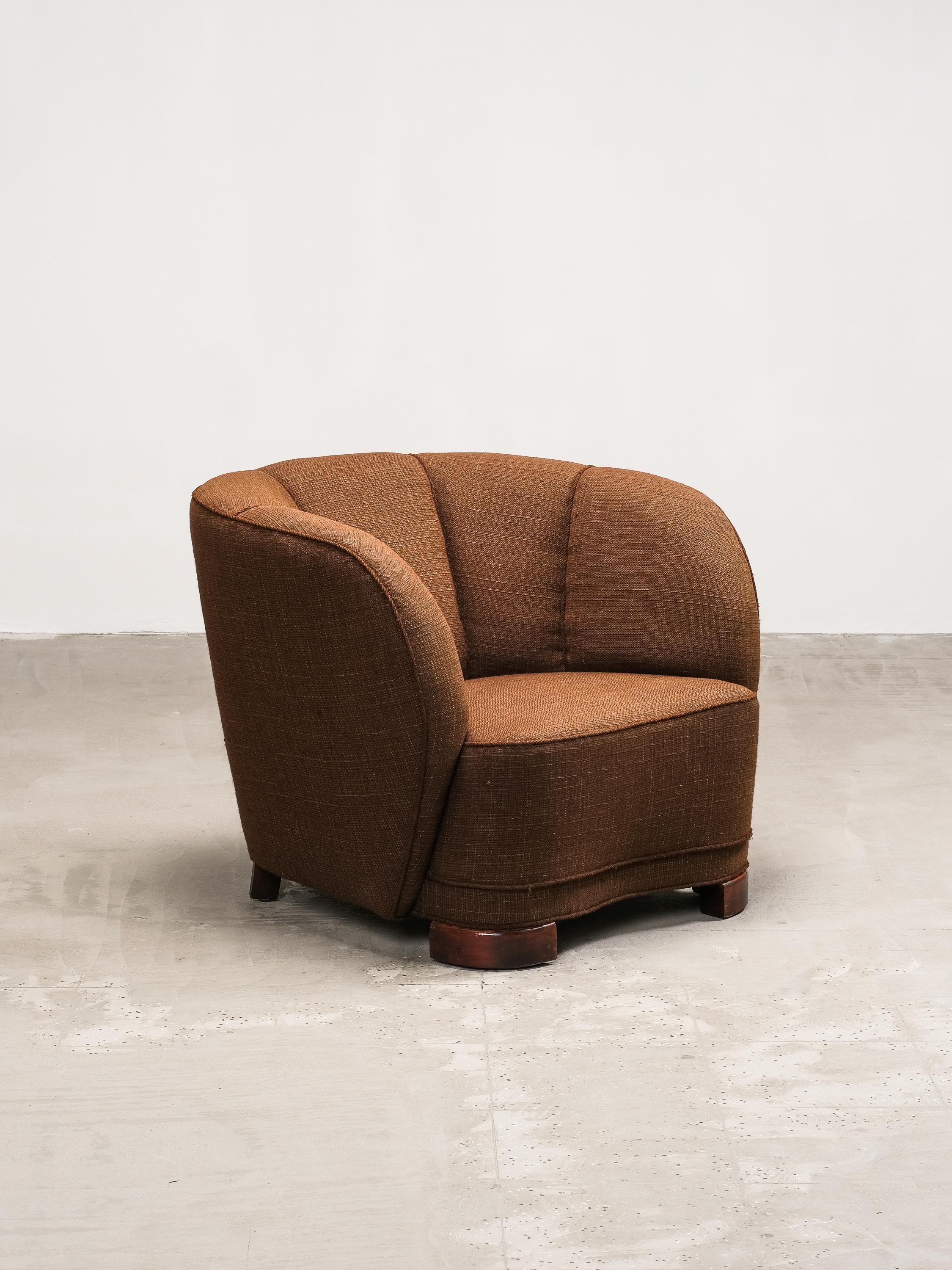 Ejemplo bellamente esculpido del diseño danés de mediados de siglo, este sillón club curvado de la década de 1940 captura la refinada elegancia y las líneas orgánicas características del modernismo escandinavo. Su acogedora silueta presenta un